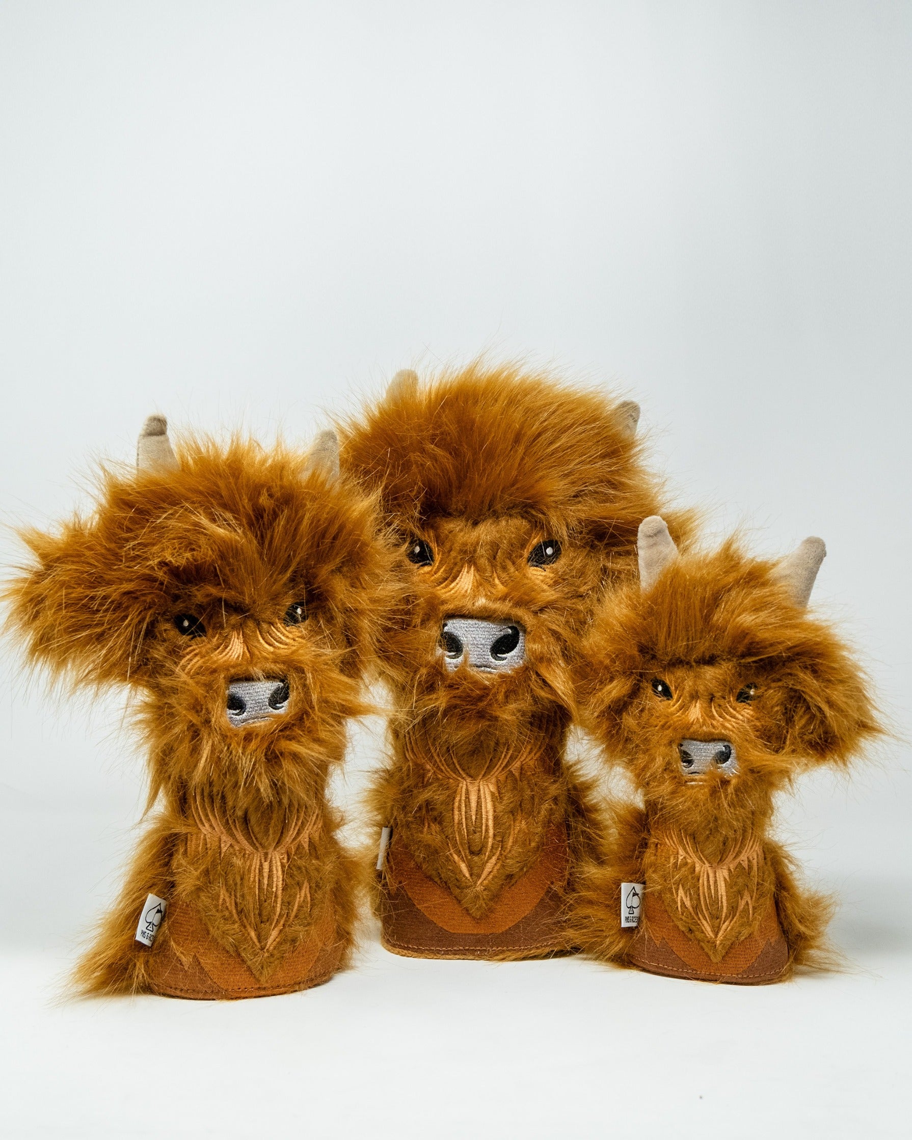 Highland cow hybrid golf headcovers in varying sizes, featuring soft fur and detailed facial features for a unique look.