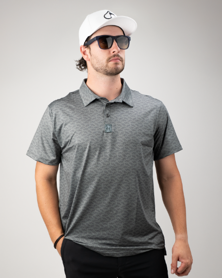 Stylish golfer wearing a gray patterned polo shirt, sunglasses, and a white cap, showcasing bold golf apparel.