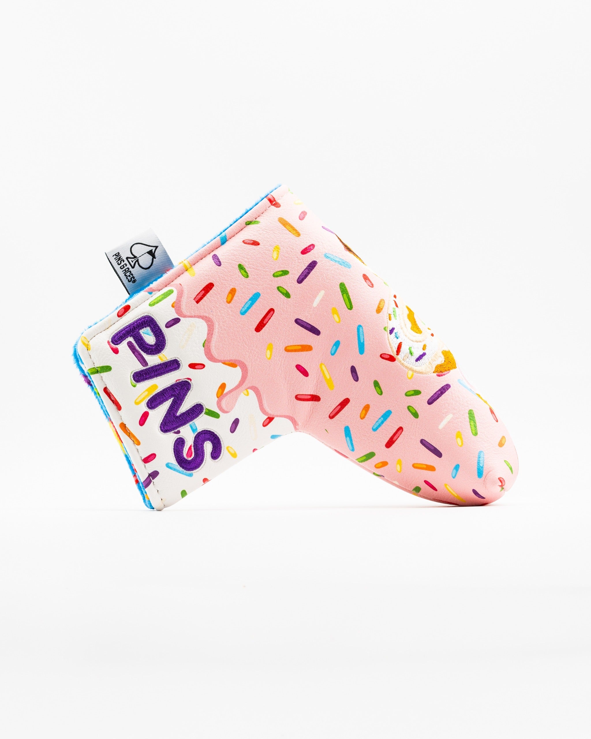 Colorful blade putter cover featuring a donut design with sprinkles and the word "PINS" for a fun, standout golf accessory.