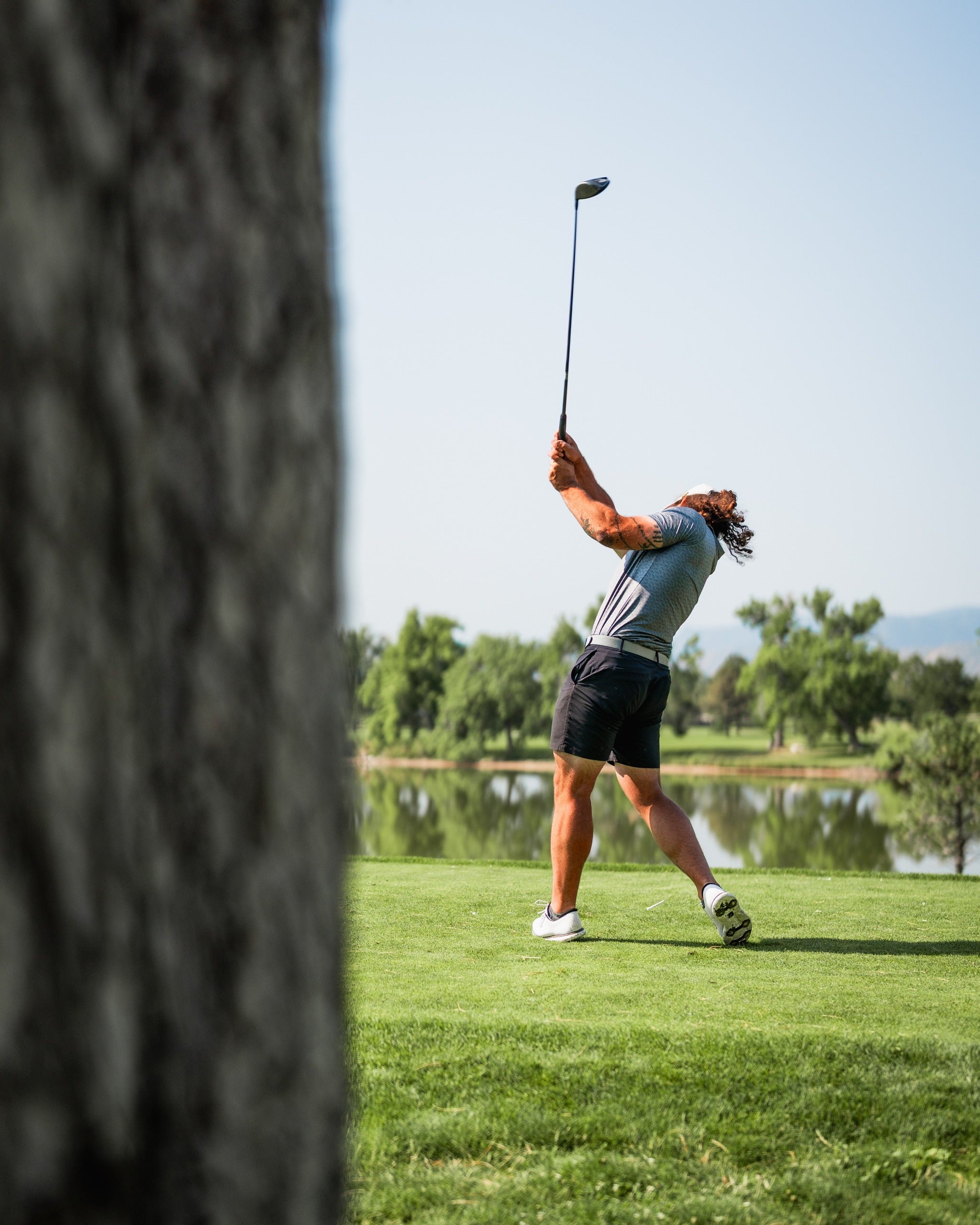 A golfer swings a club on a sunny course, showcasing bold golf apparel and a dynamic golf pose.