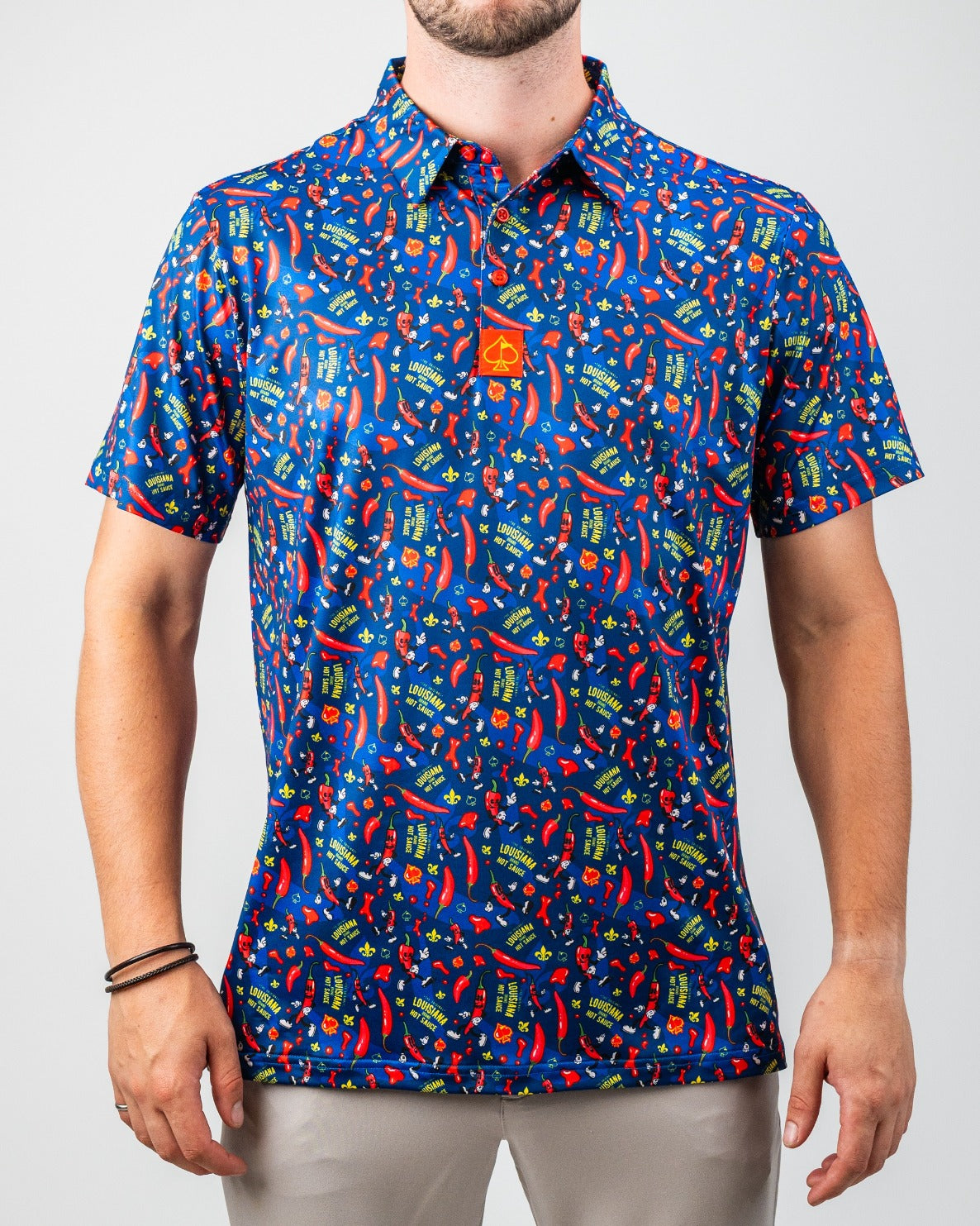 Bright blue golf shirt with red chili peppers, "Louisiana Hot Sauce" text, and yellow fleur-de-lis, perfect for bold on-co...