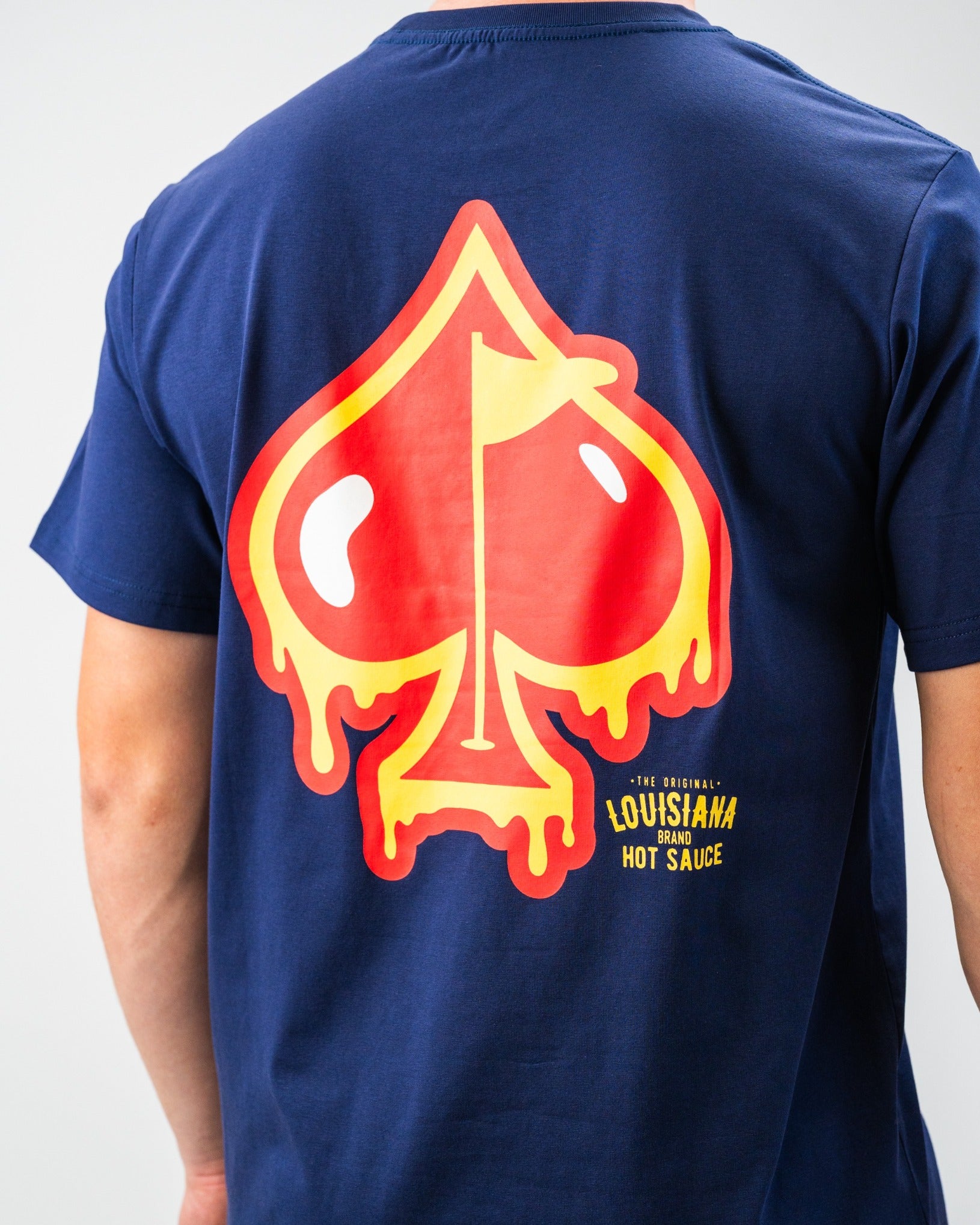 Bold navy t-shirt with a large, colorful hot sauce skull graphic and "Louisiana Brand Hot Sauce" text on back.