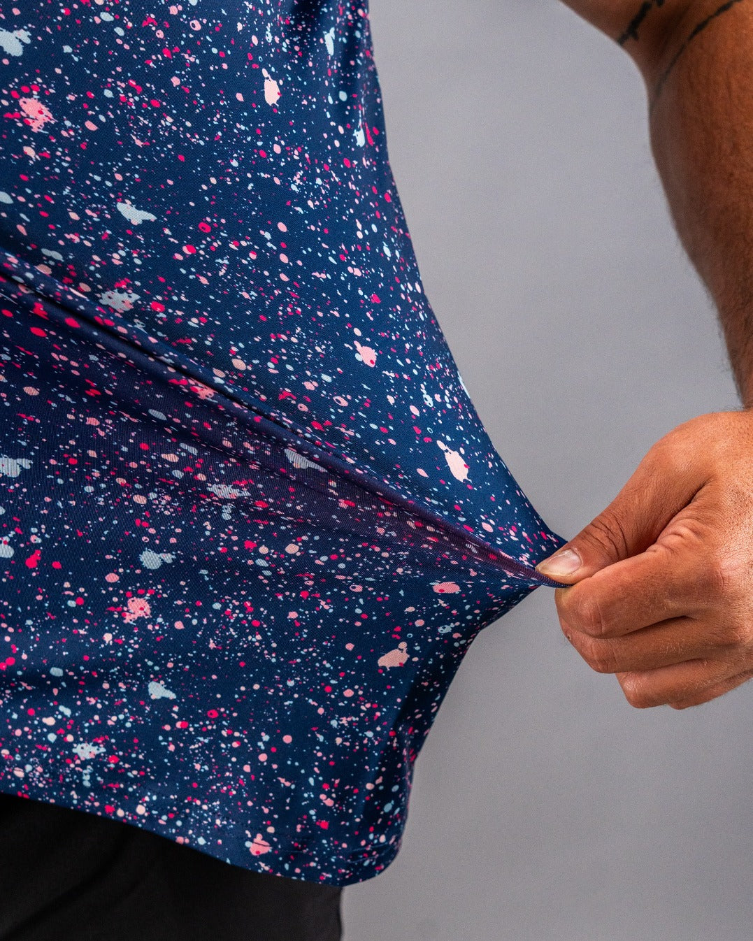 Bold blue golf shirt featuring a vibrant splatter pattern in pink and white, showcasing a unique and stylish design.