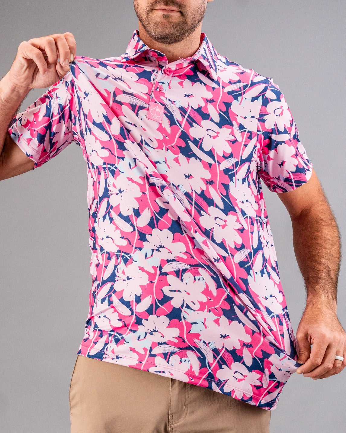 Man wearing a bold pink, navy, and white floral golf shirt, perfect for standing out on the course.