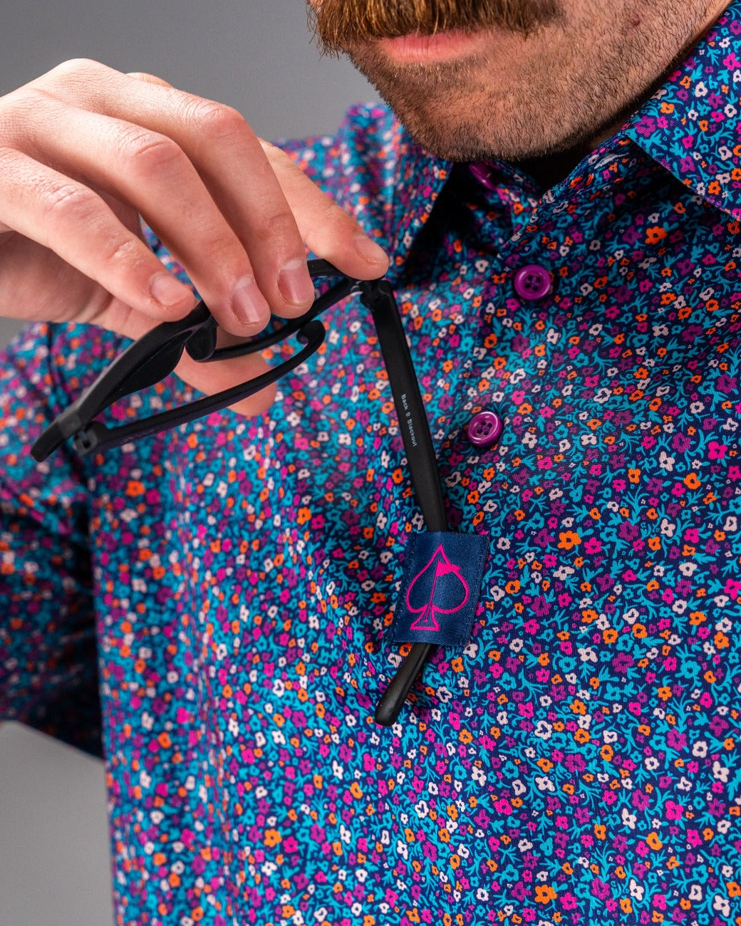 Bold floral golf shirt featuring vibrant lavender hues, with a stylish collar and a pocket for sunglasses.