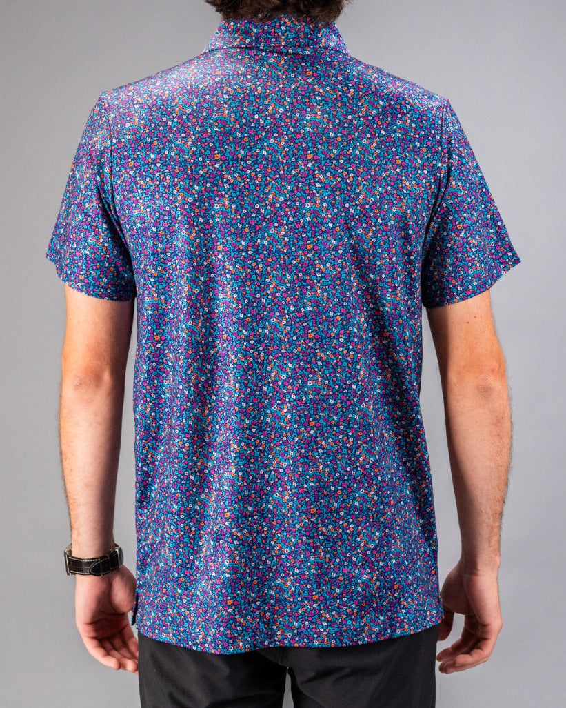 Men's short-sleeve golf shirt featuring a vibrant lavender floral print against a dark background, designed for standout style on the course.