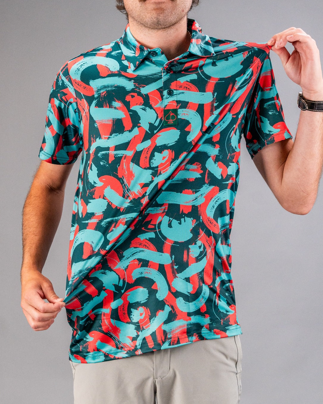 Bold golf polo featuring a vibrant coral and teal paint stroke pattern, perfect for golfers seeking unique style on the course.