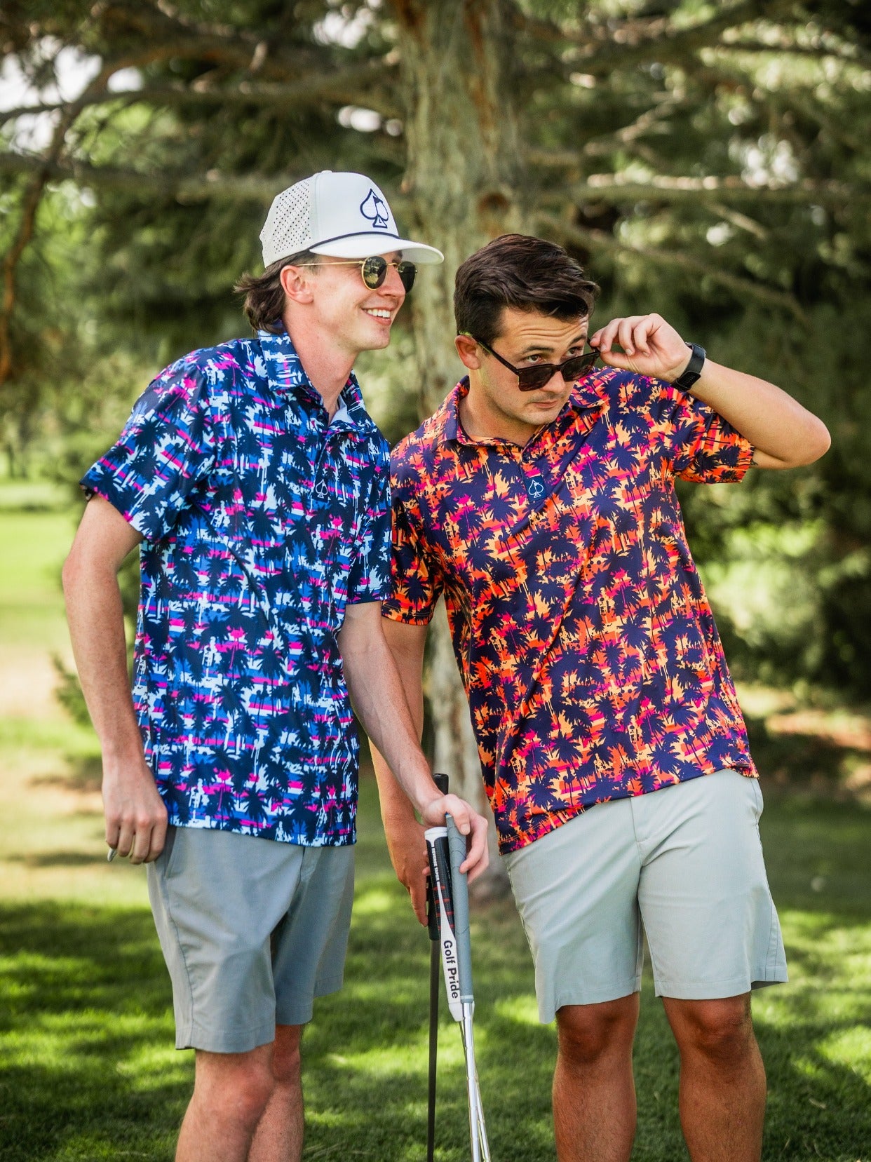 Two men in colorful, bold Hawaiian shirts and sunglasses, enjoying a sunny day on the golf course with trees in the backgr...