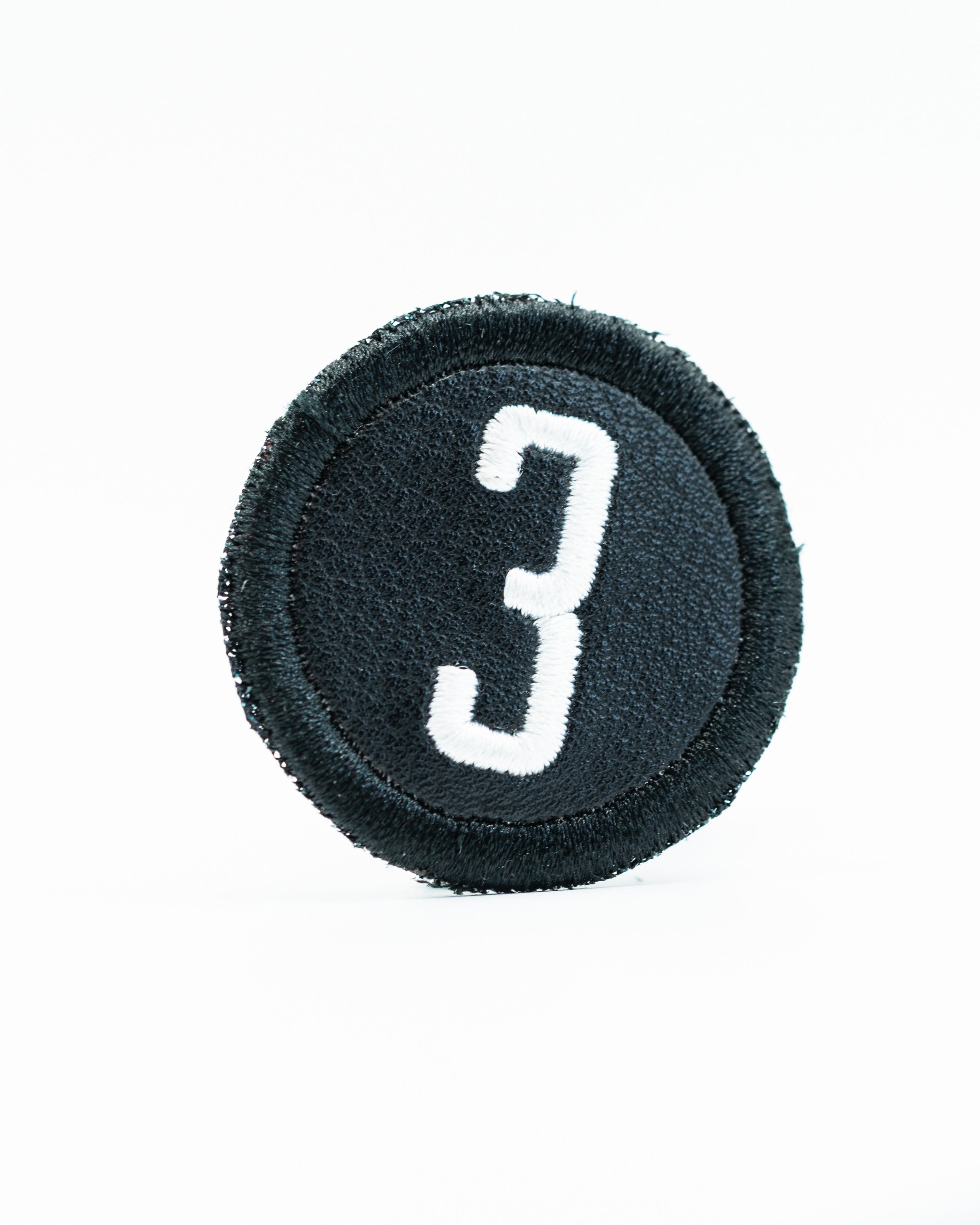 Black headcover patch featuring a bold white number three, designed for golfers to personalize their gear.