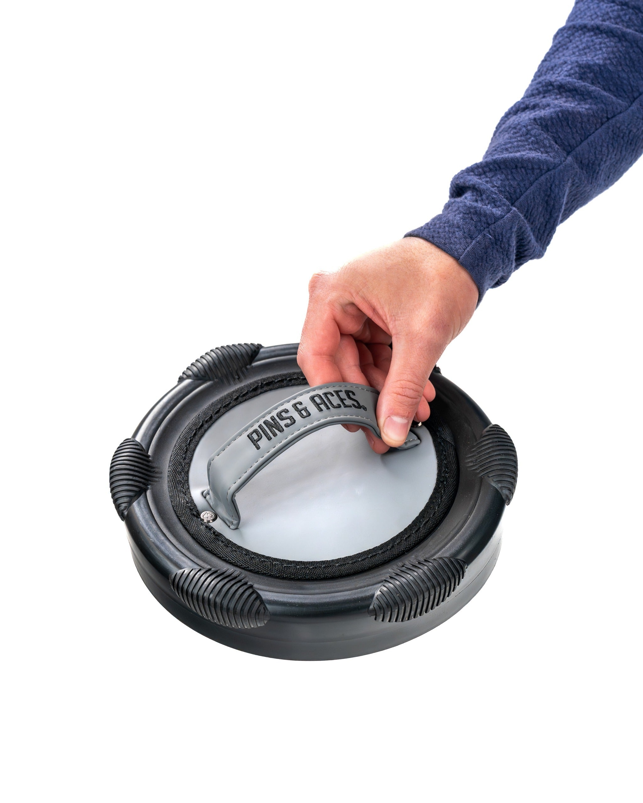 Hand gripping the handle of the Den Caddy - Flat Ash, a sleek golf accessory designed for easy transport and organization.