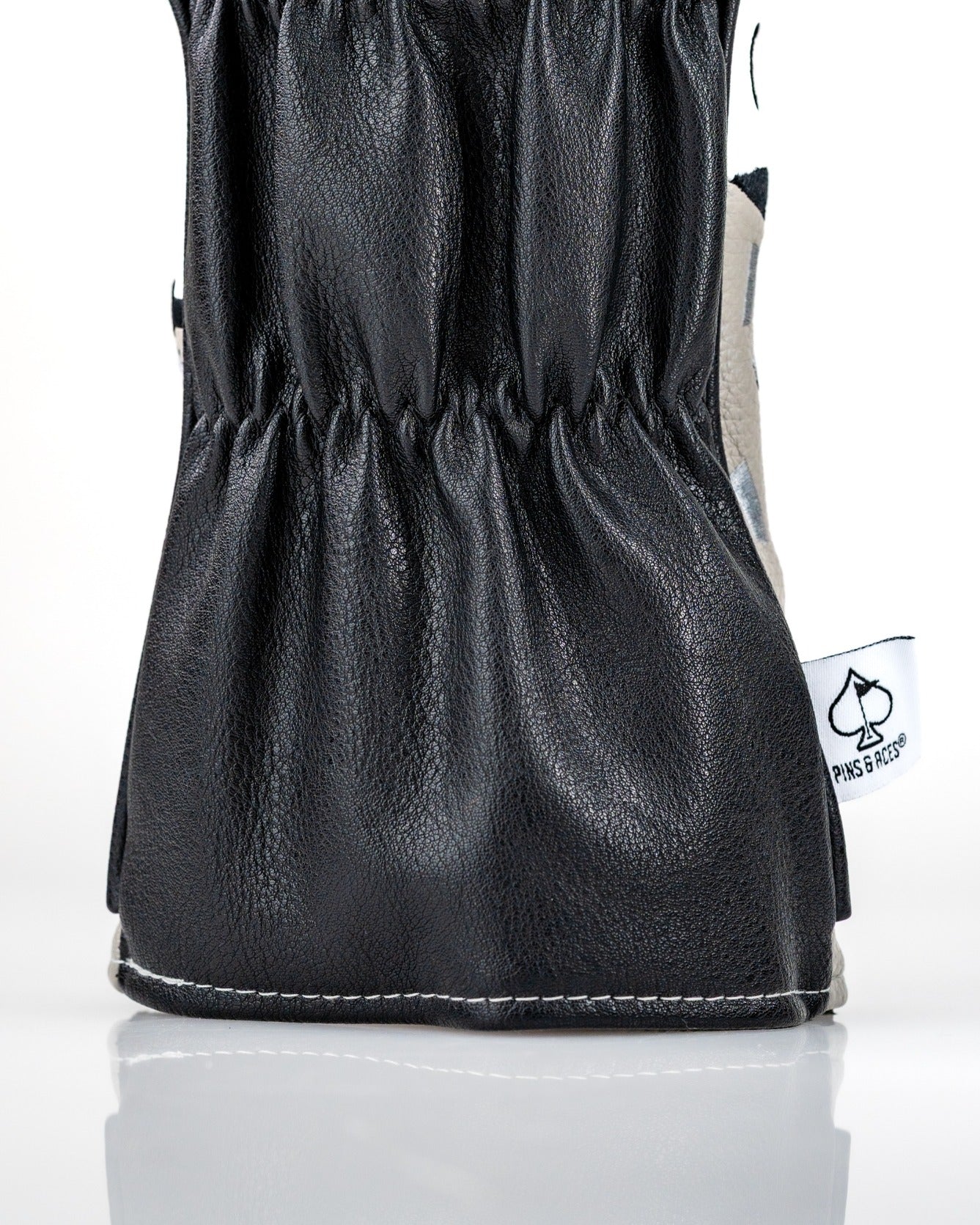 Stylish black leather driver cover with a gathered design, featuring the Pins and Aces logo for a bold golf statement.
