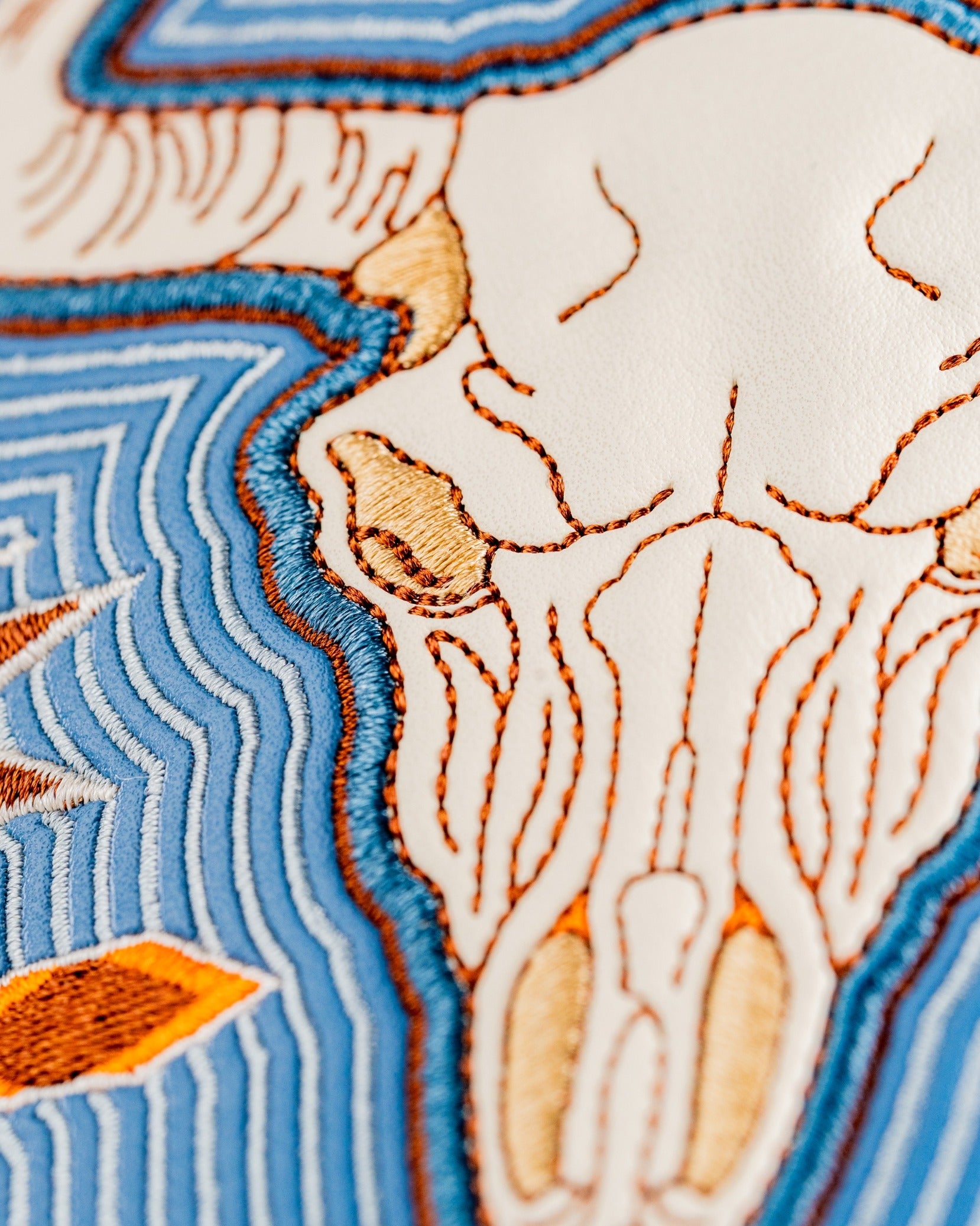 Western aesthetic driver cover featuring intricate stitching of a skull design on a textured background.