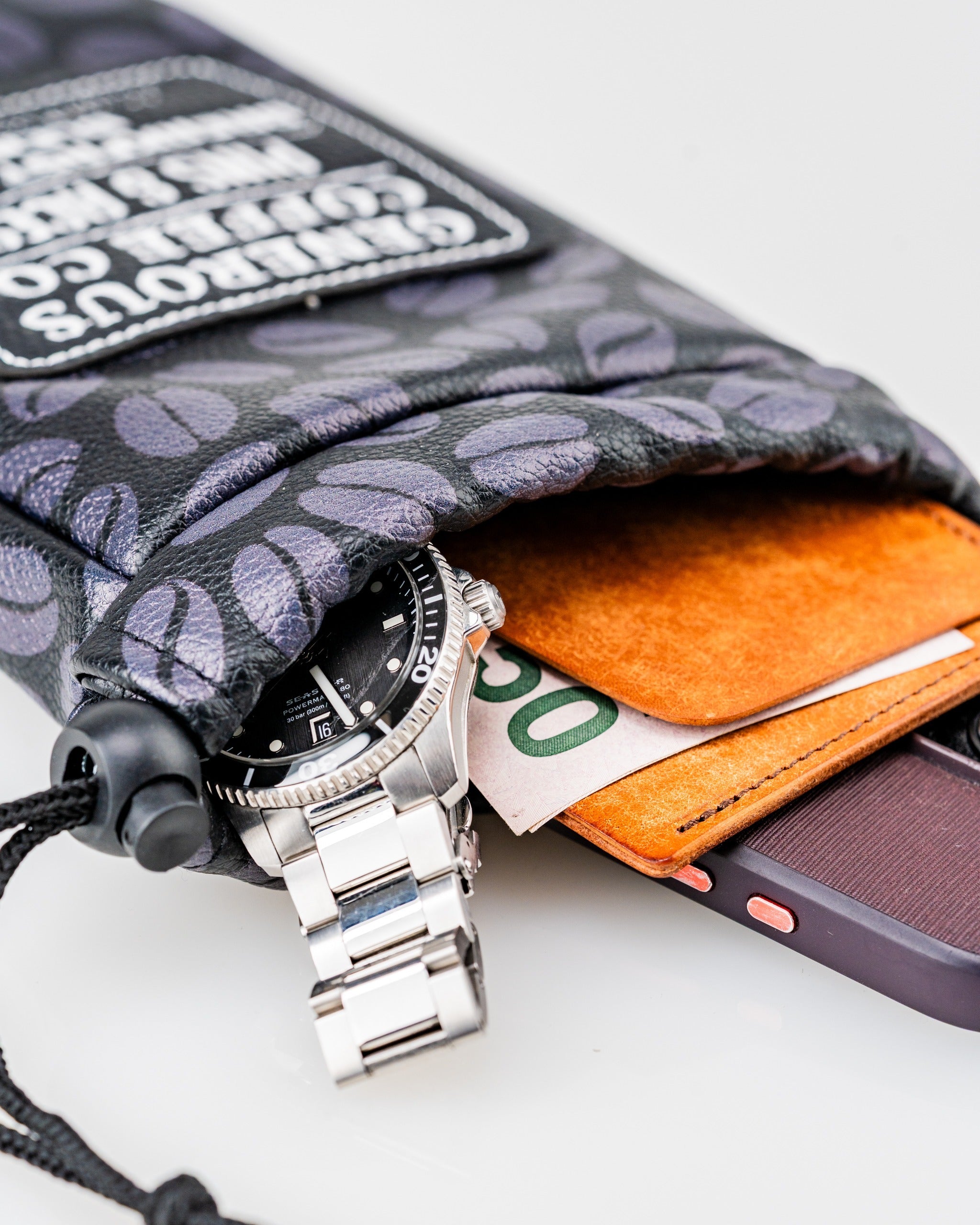 Valuables pouch featuring a stylish design, holding a watch, cash, and a phone for secure storage.