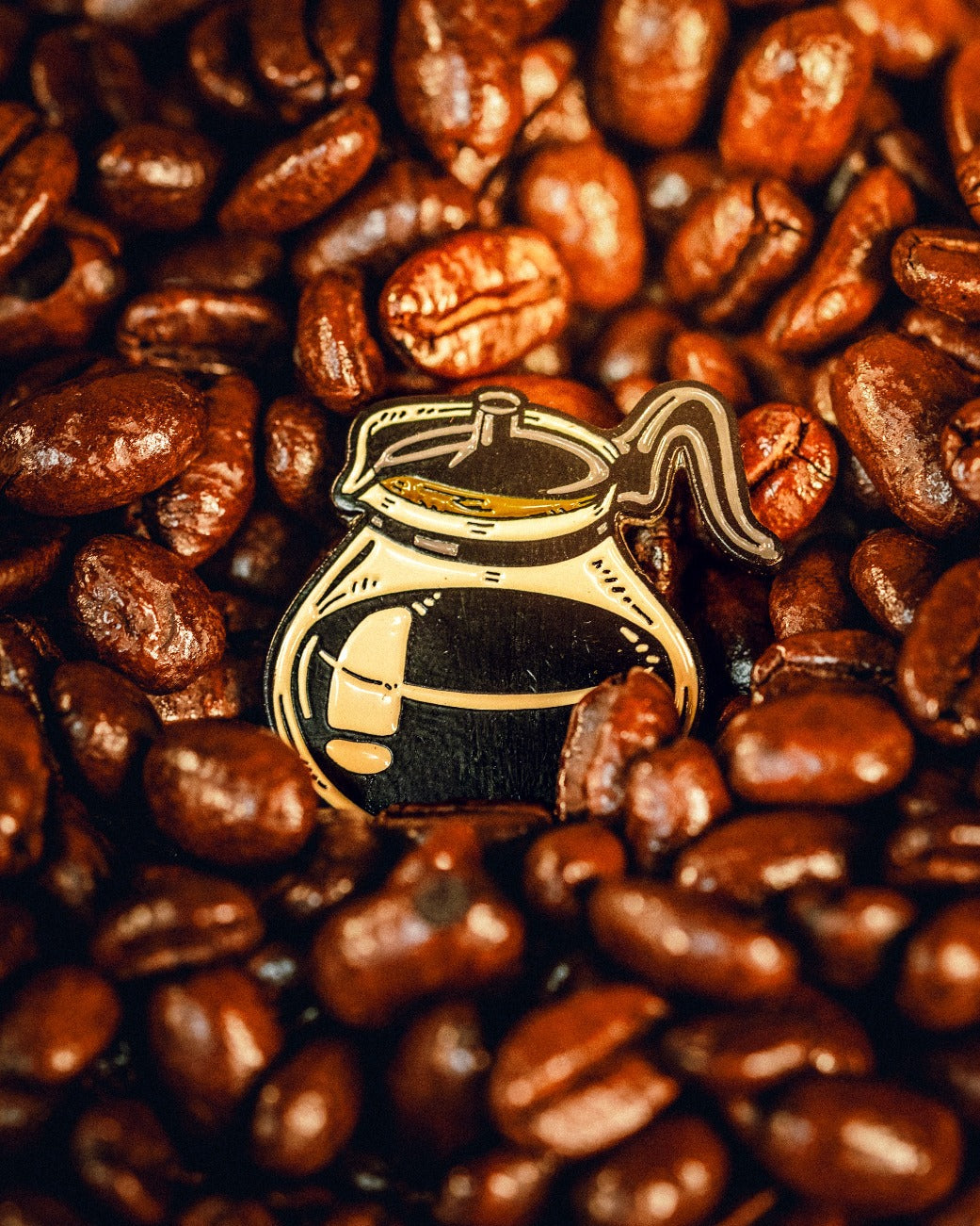 Pot of coffee ball marker surrounded by roasted coffee beans, perfect for coffee-loving golfers.