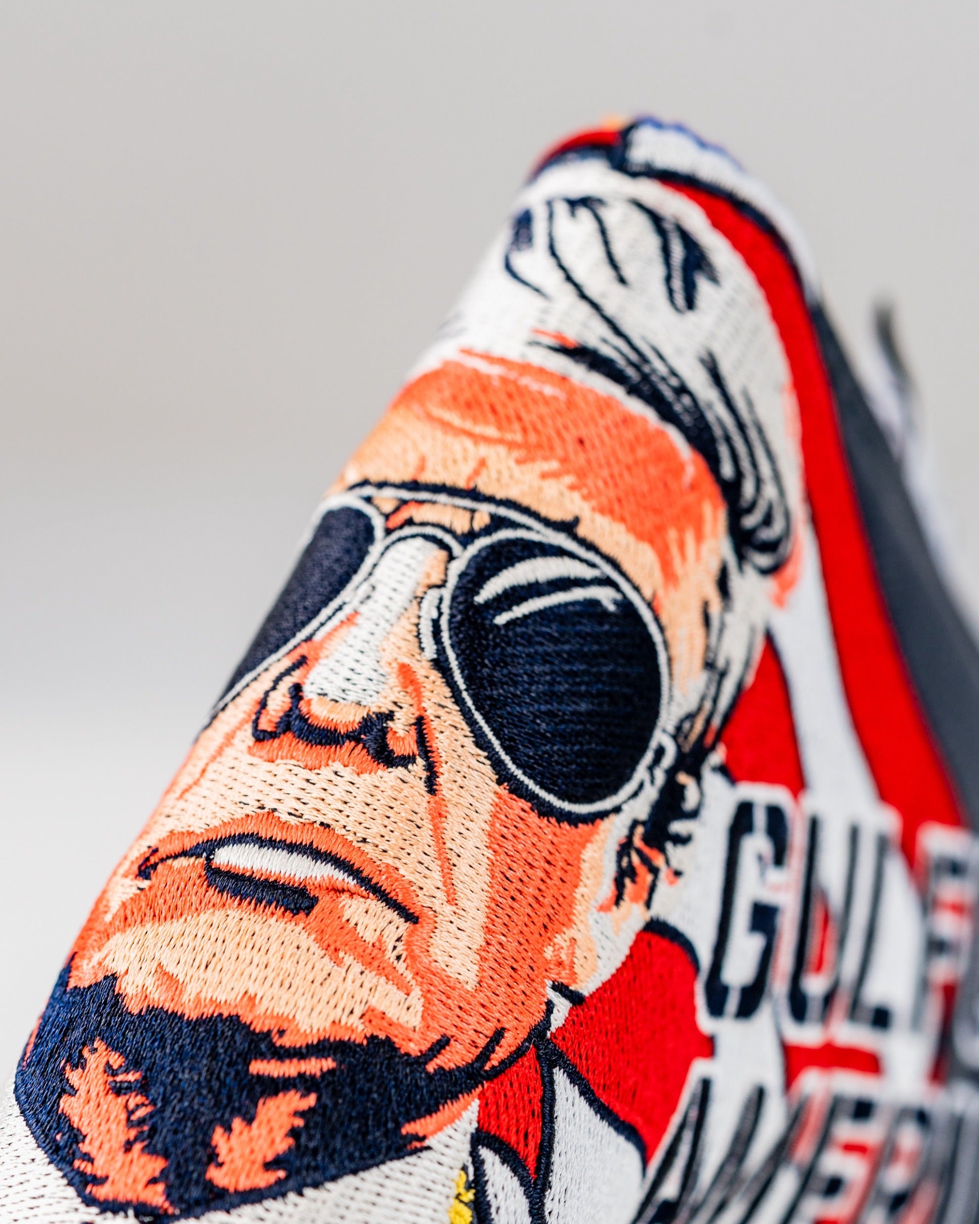 Bold golf blade cover featuring an embroidered design of a character with sunglasses and patriotic colors, ideal for standout style on the course.