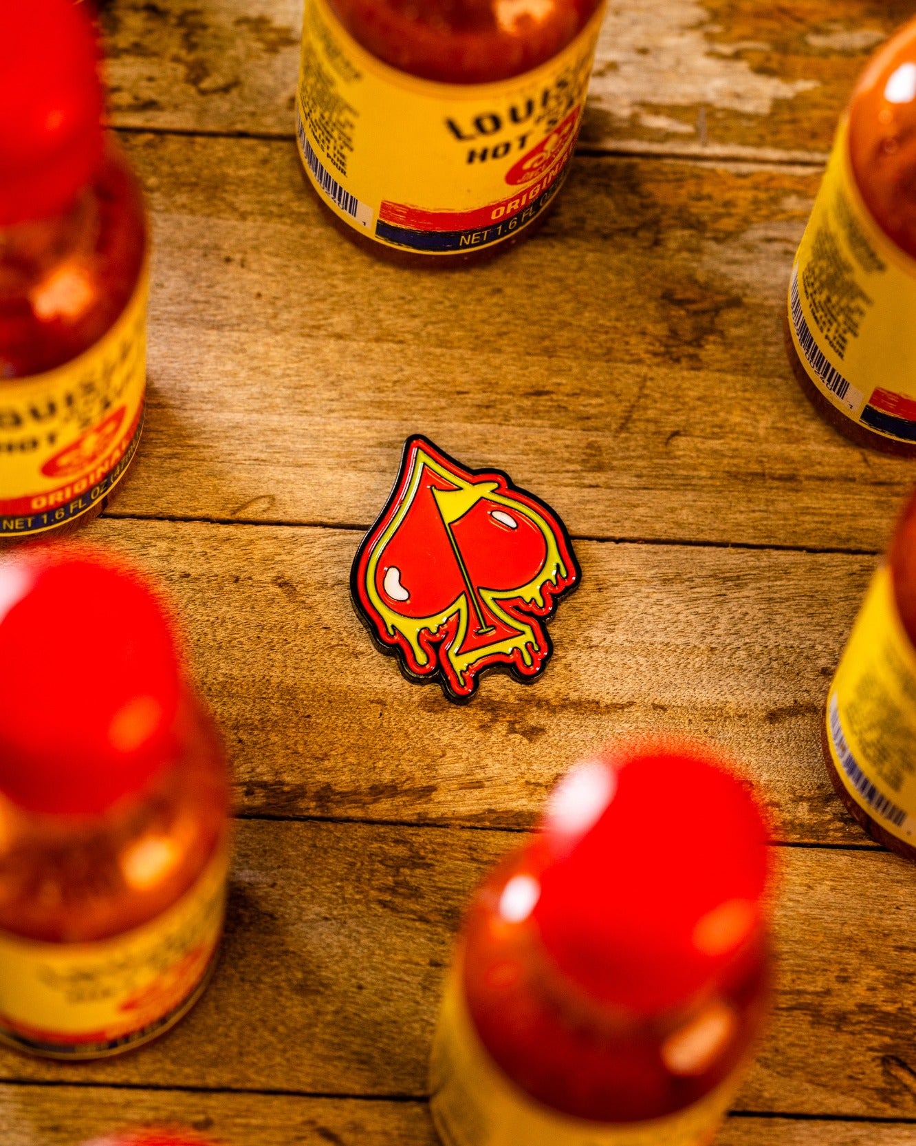 Bold Flamin' Spade ball marker featuring a fiery spade design, surrounded by hot sauce bottles on a wooden surface.