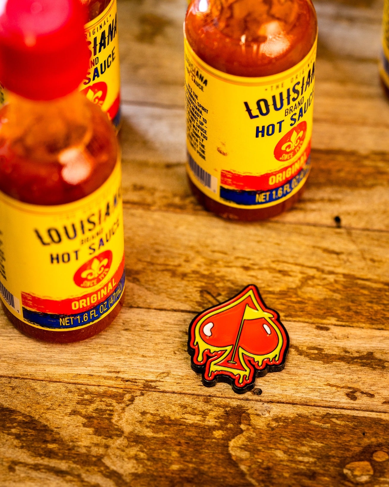 Bold Flamin' Spade ball marker featuring a dripping spade design, surrounded by hot sauce bottles on a wooden surface.