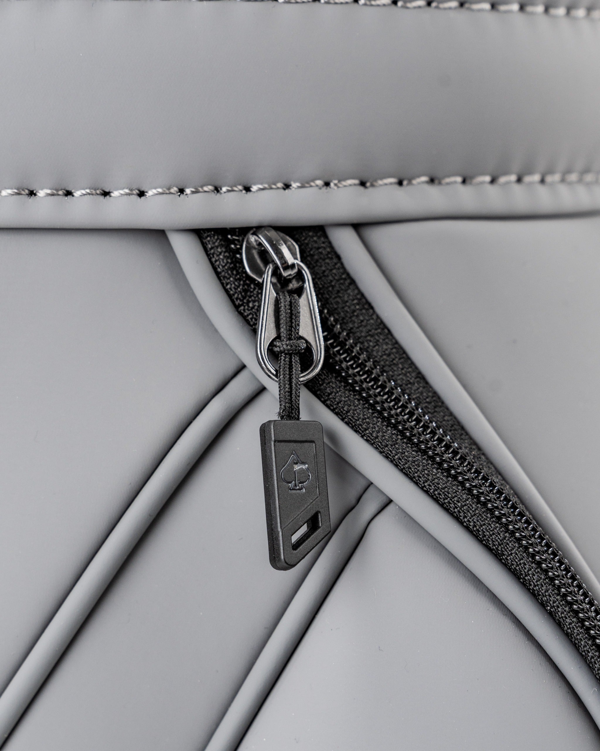 Close-up of the Den Caddy in Flat Ash, showcasing a sleek zipper detail on a textured, modern golf accessory.
