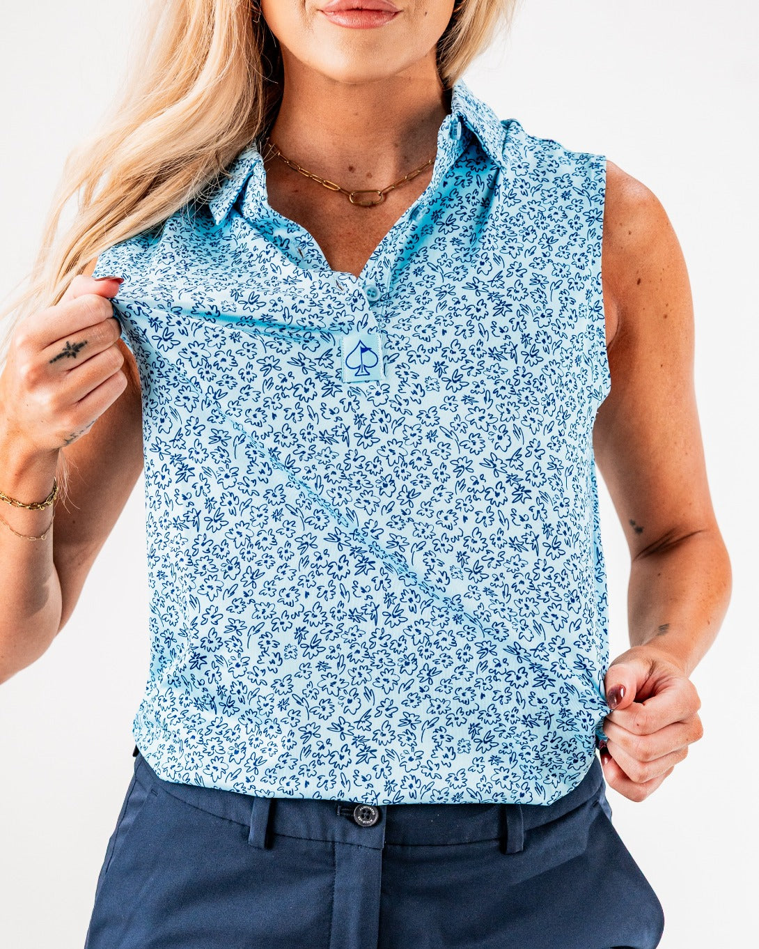 Women's sleeveless blue shirt featuring a floral doodle pattern, perfect for stylish golf outings.