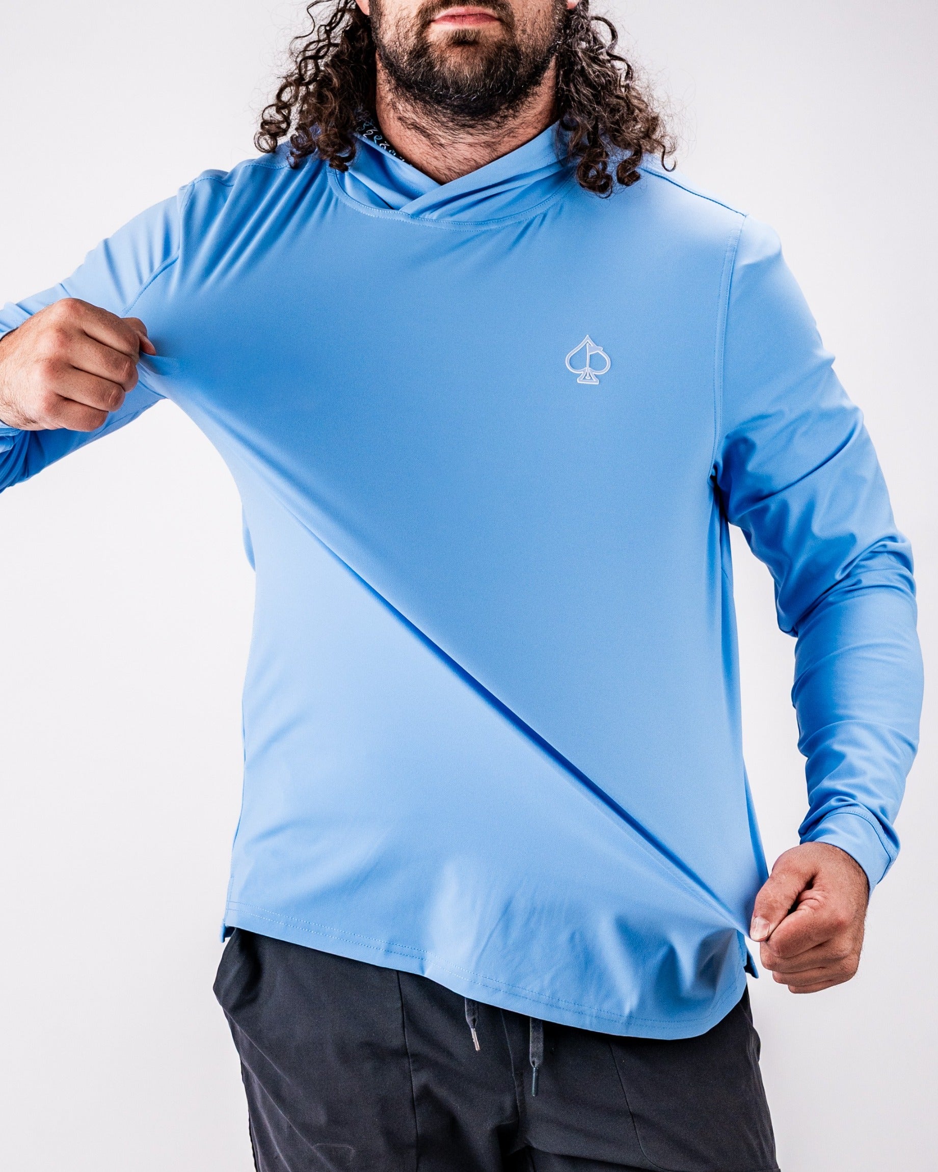 Man wearing a light blue Performance Golf Hoodie - Rising Tides 2.0, showcasing its stretchable fabric and design.