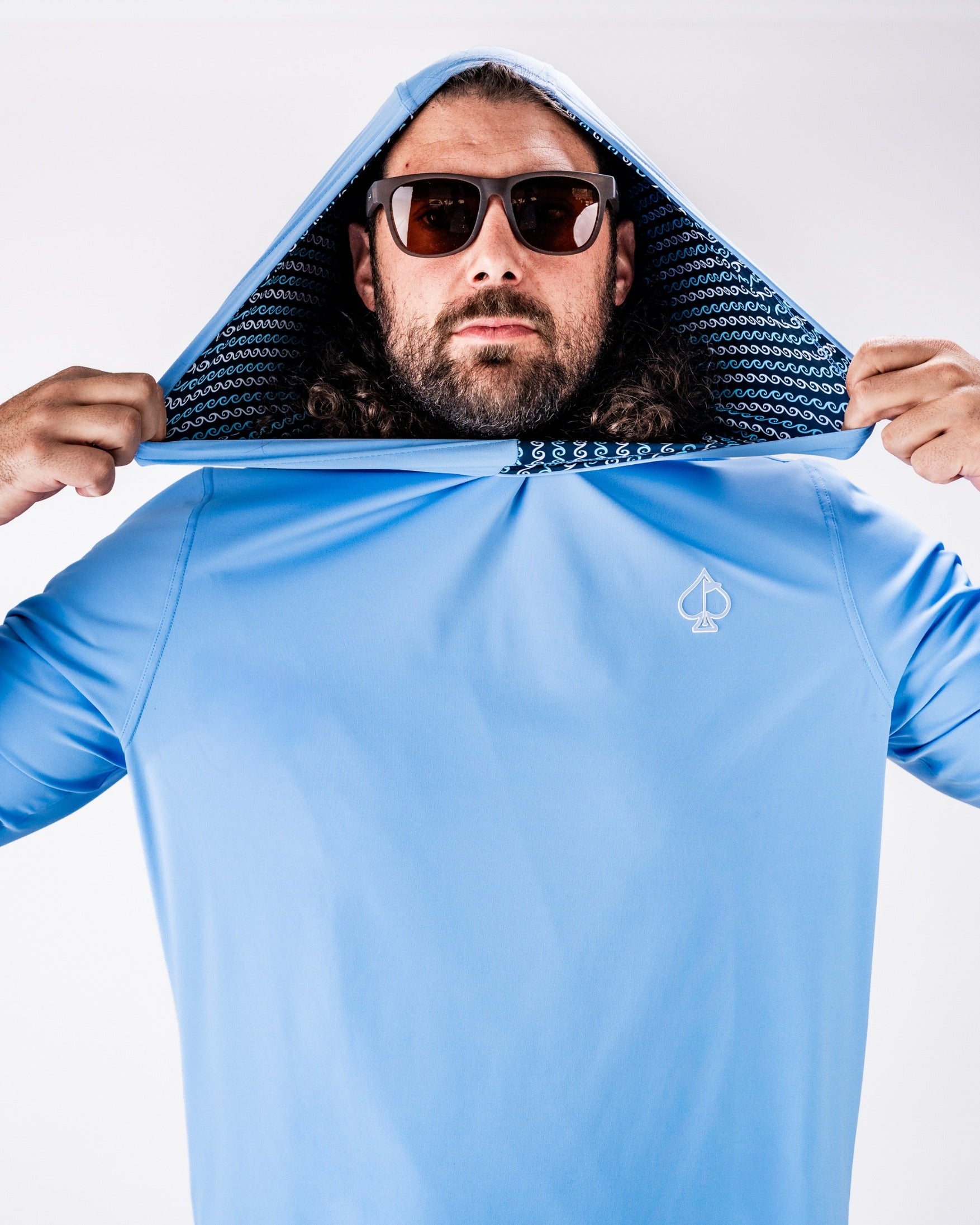 Man wearing a light blue performance golf hoodie with a unique patterned interior, showcasing a stylish and sporty look.