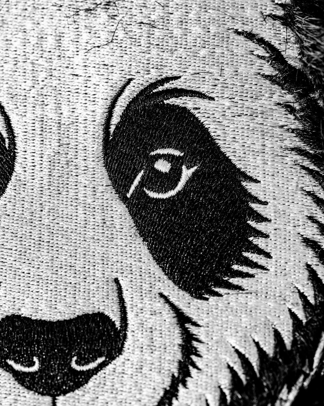 Close-up of a panda driver cover featuring detailed black and white embroidery of a panda's face and eye.