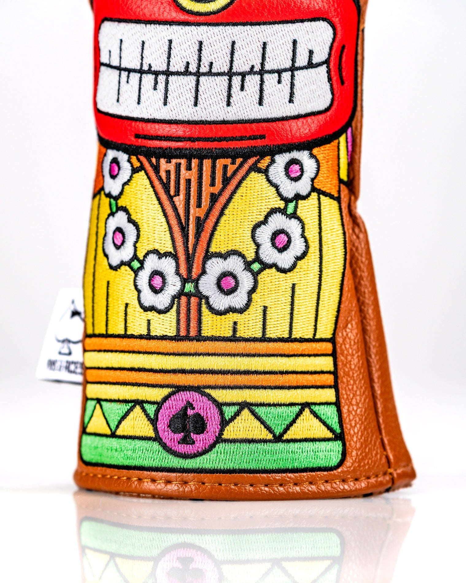 Colorful Tiki hybrid golf club cover featuring a vibrant design with floral accents and a playful tiki face.