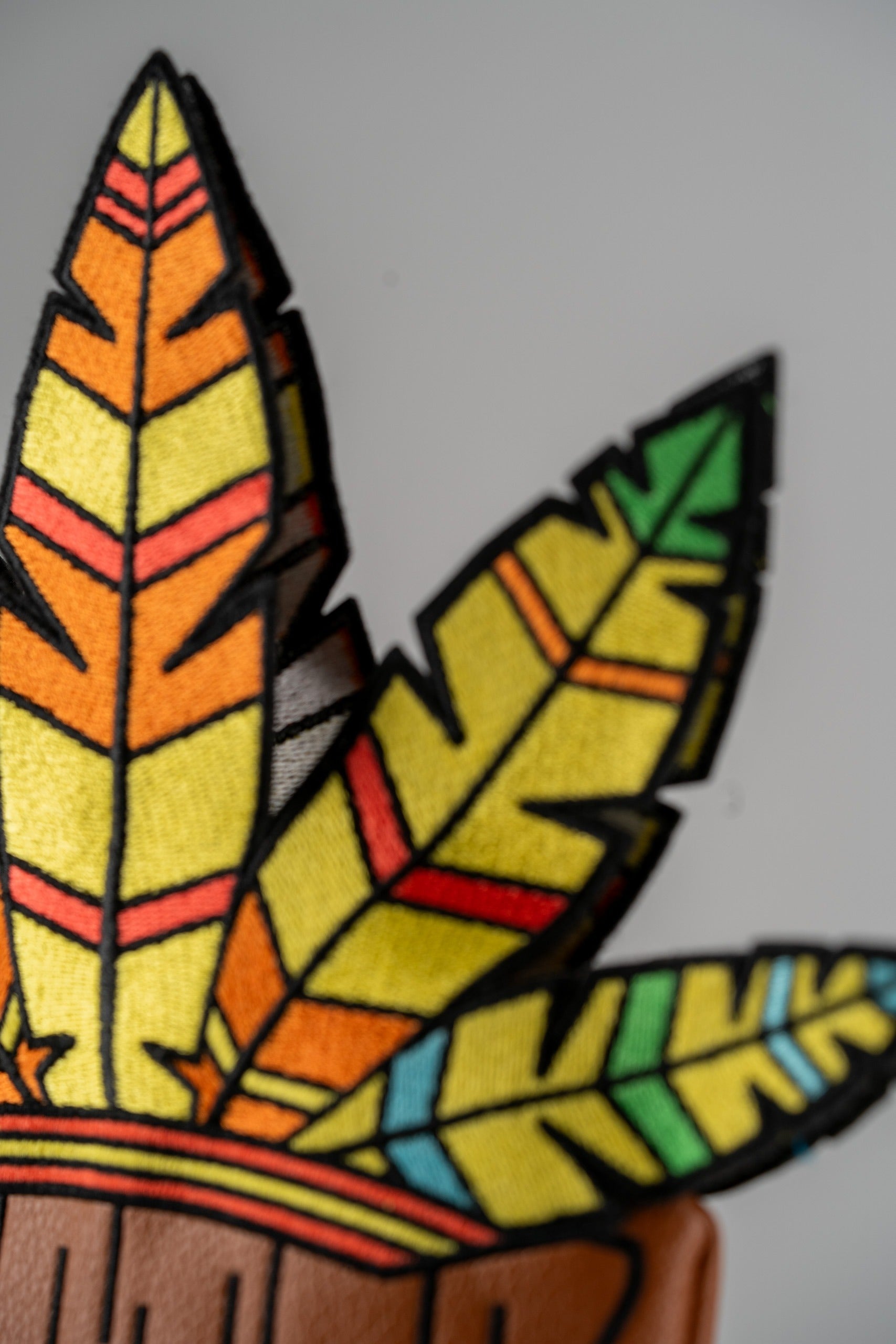 Colorful Tiki driver cover featuring vibrant feather designs in orange, yellow, green, and black for a bold golf style.