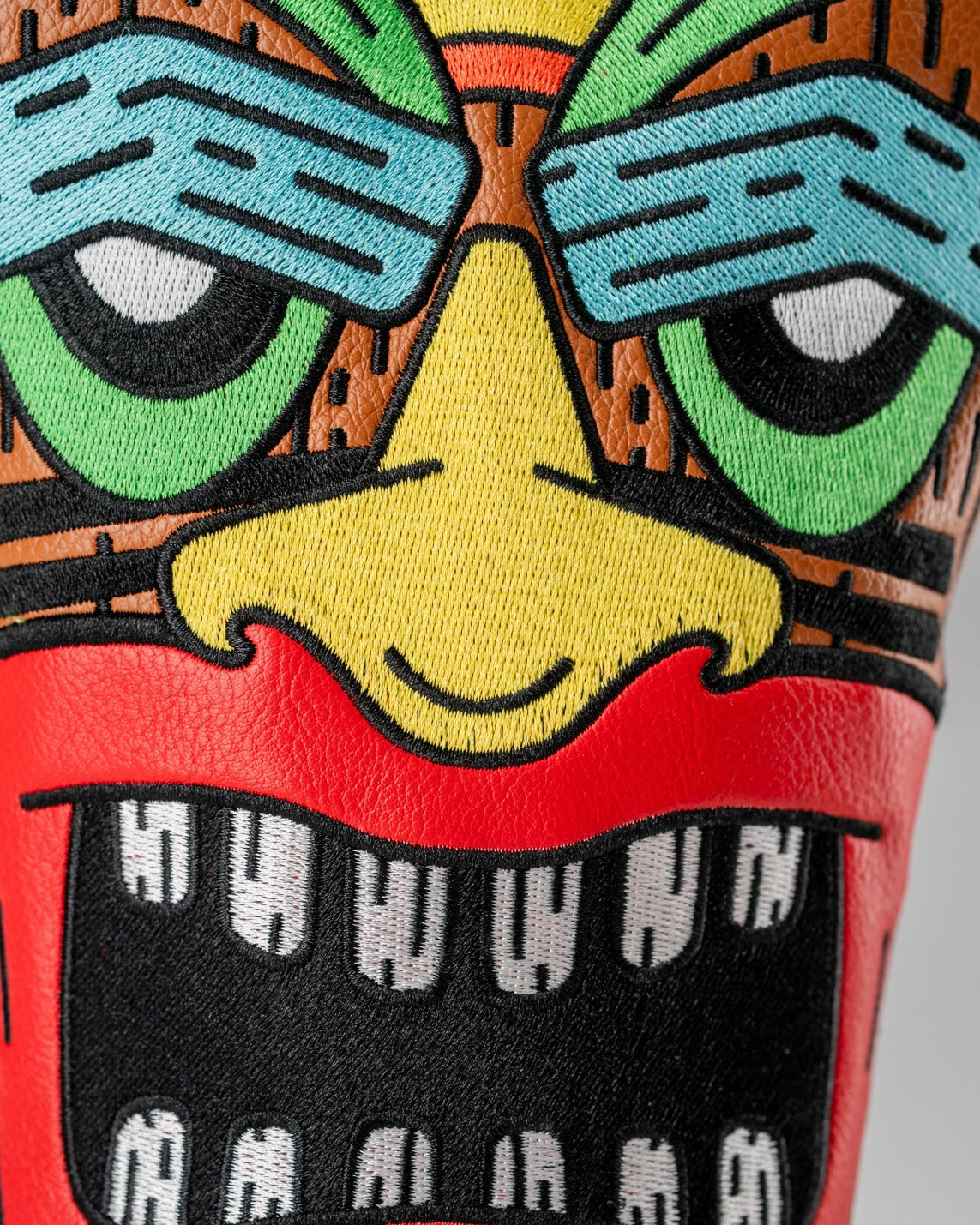 Colorful Tiki driver cover featuring a vibrant face design with bold colors and intricate detailing for a unique golf accessory.