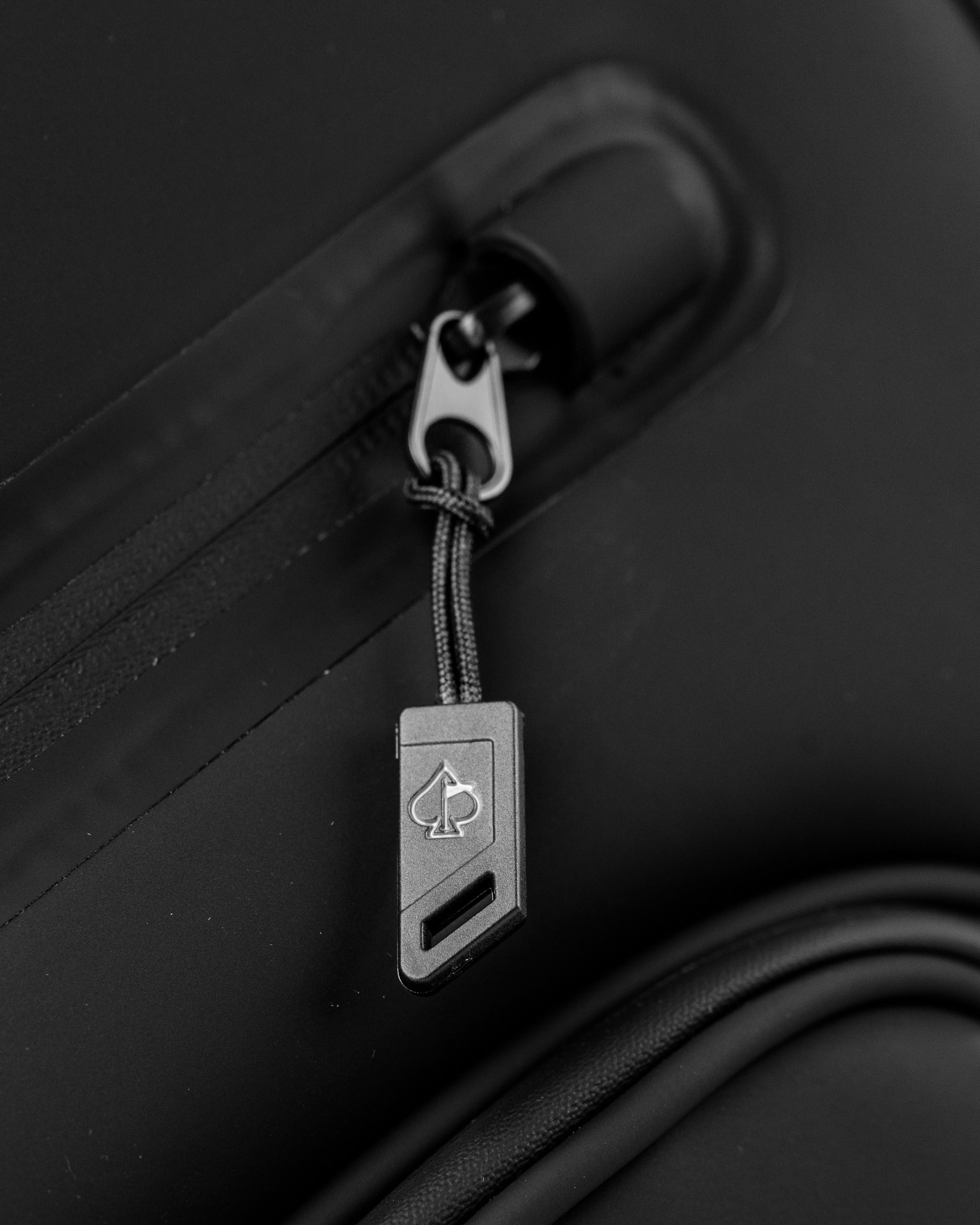 Close-up of the zipper pull on the Player Preferred™ Cart Bag in black, showcasing a sleek design and logo detail.