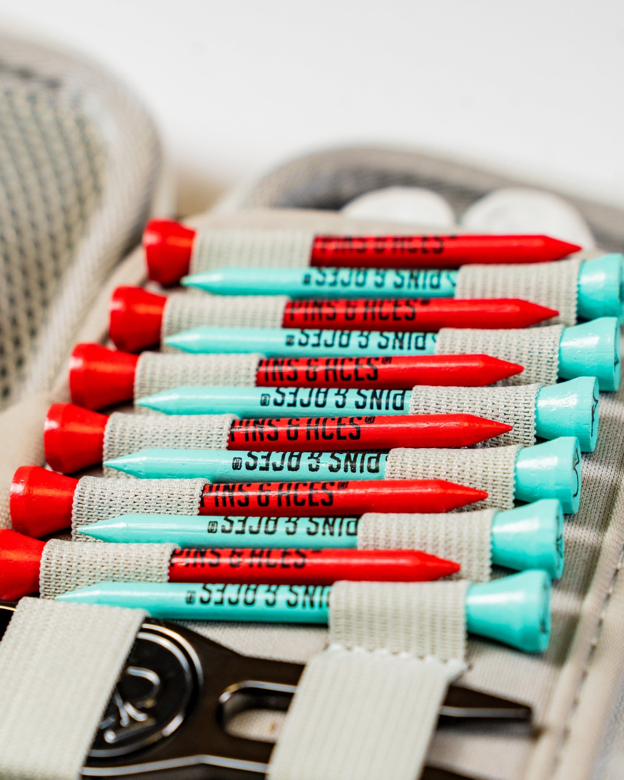 Gray glove and accessory caddie featuring organized golf tees in red and teal, designed for easy access on the course.