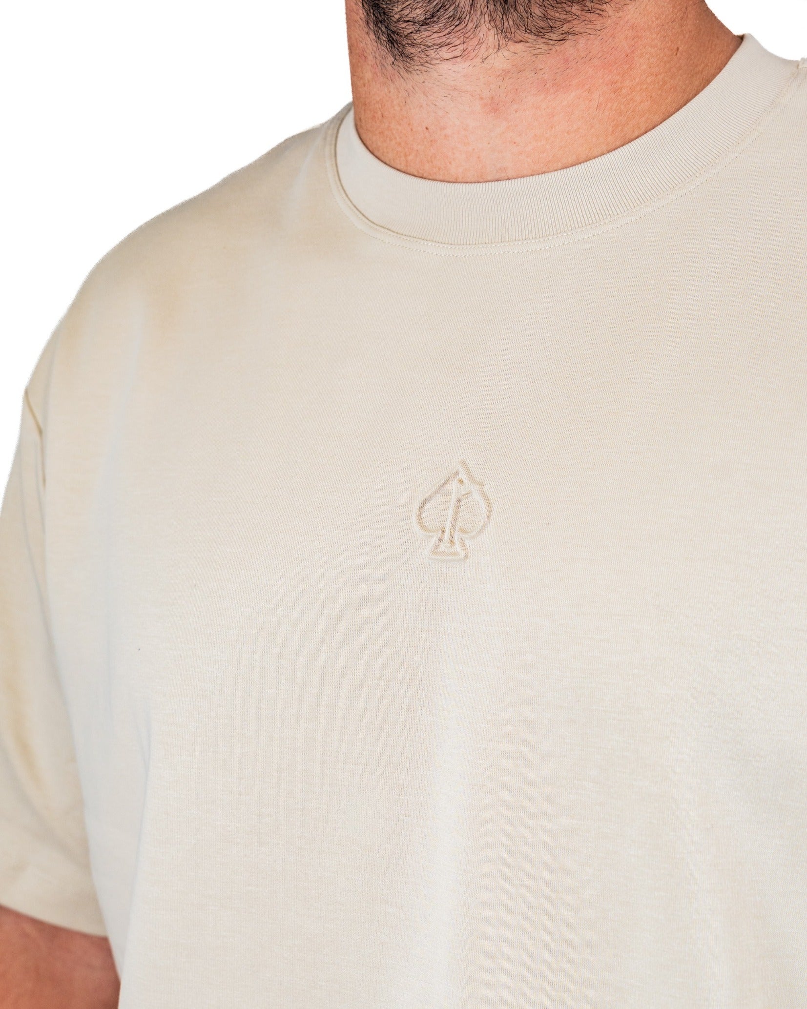 Cream embossed spade tee shirt featuring a subtle spade logo, designed for a stylish and bold golf look.