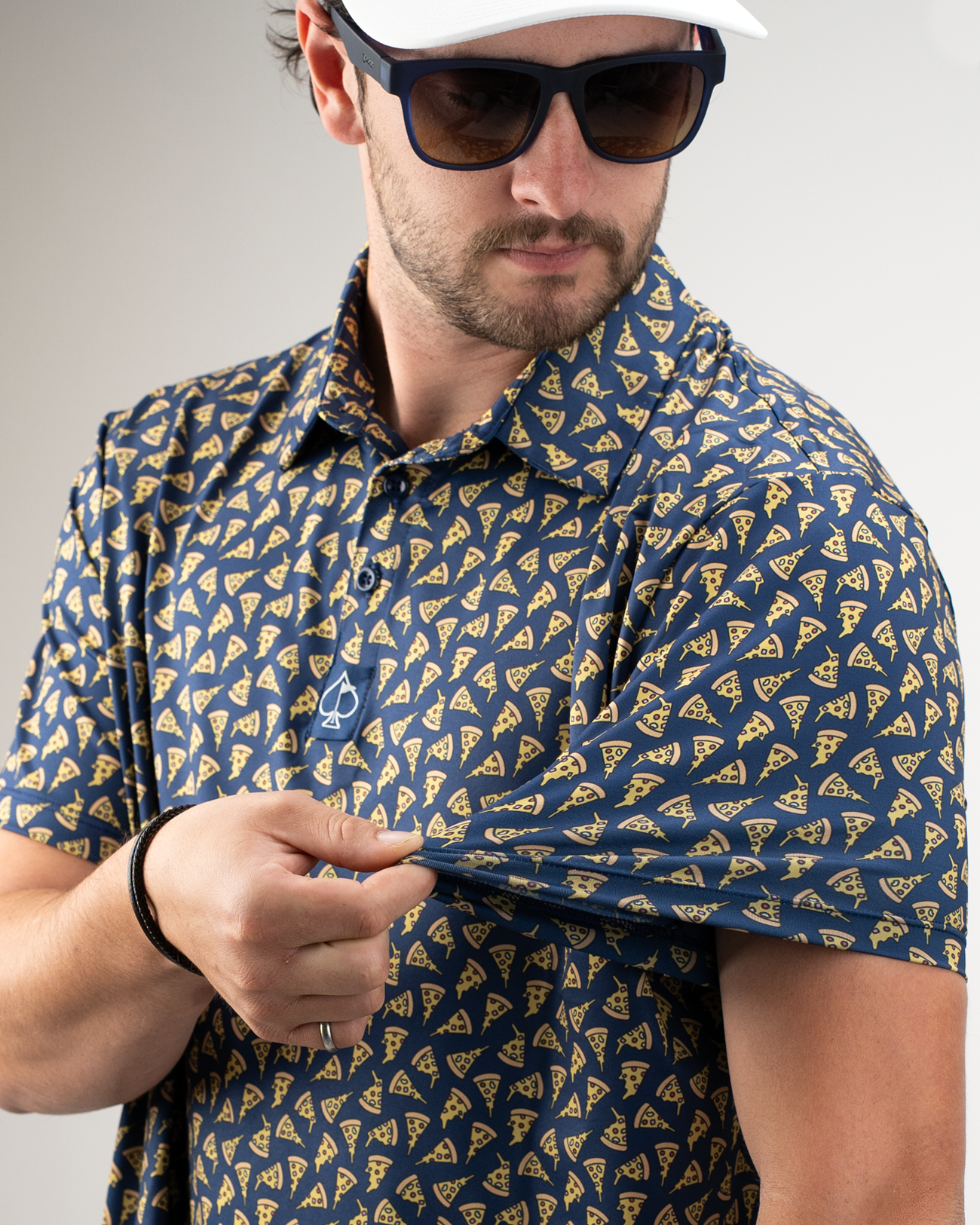 A man wearing a navy golf shirt featuring a playful pizza slice pattern, showcasing the shirt's design.