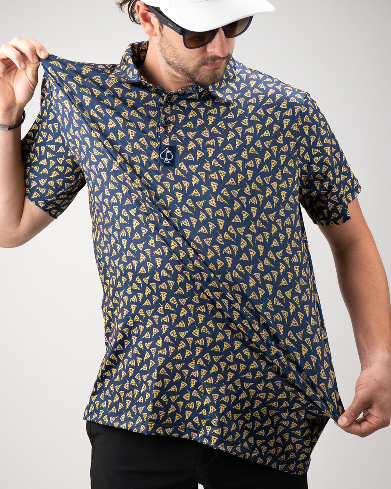 Man wearing a navy polo shirt featuring a playful pizza slice pattern, showcasing its lightweight fabric.