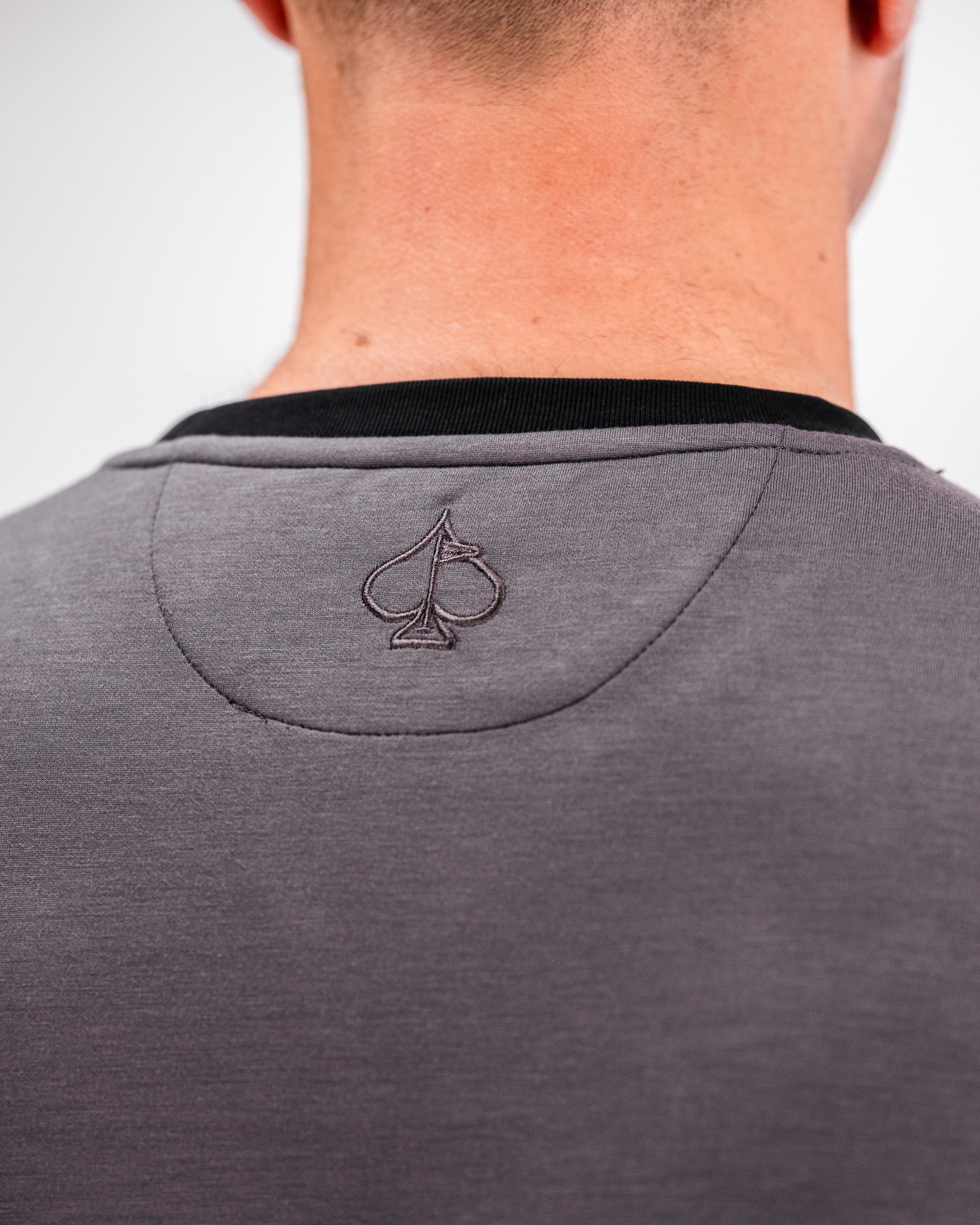 Back view of a person wearing a slate grey Player Preferred™ Crewneck with a small embroidered spade logo on the upper back.