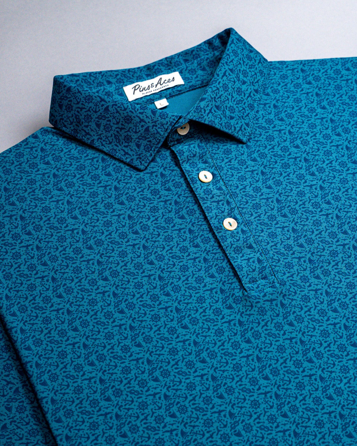 Blue Player Preferred™ Polo shirt with a nautical pattern, button-up front, and a collar, labeled "The Mariner.