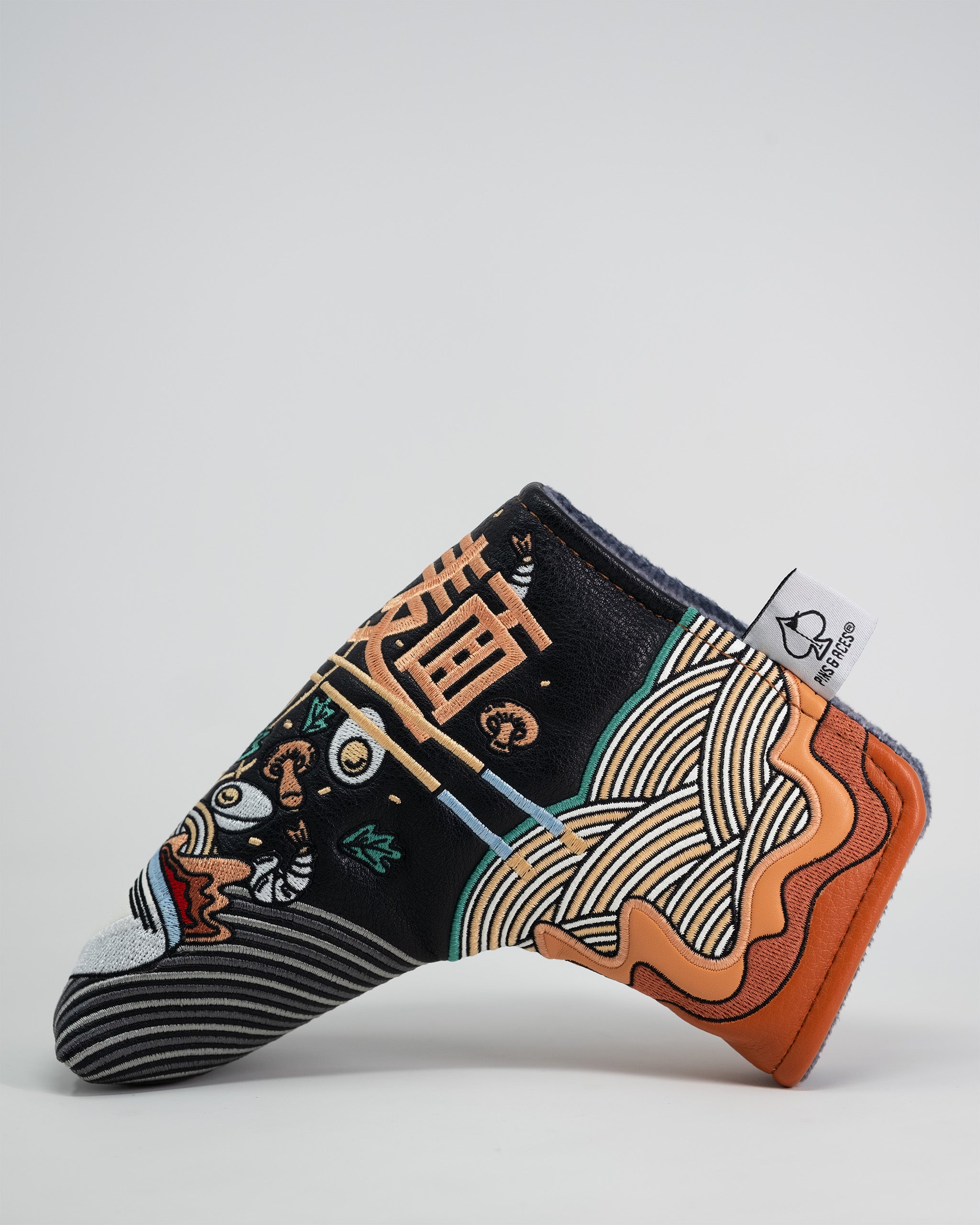 Ramen themed Blade Putter Cover with colorful noodle and chopstick design, black background, and a fabric tag.