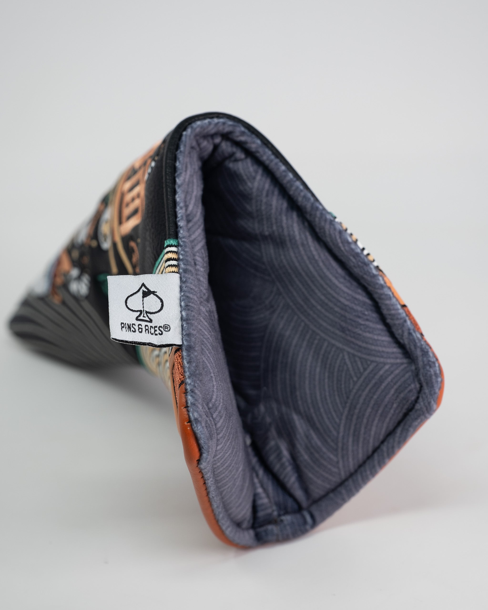 Close-up of a Pins and Aces Blade Putter Cover with a ramen-inspired design, soft interior lining, and a branded tag.