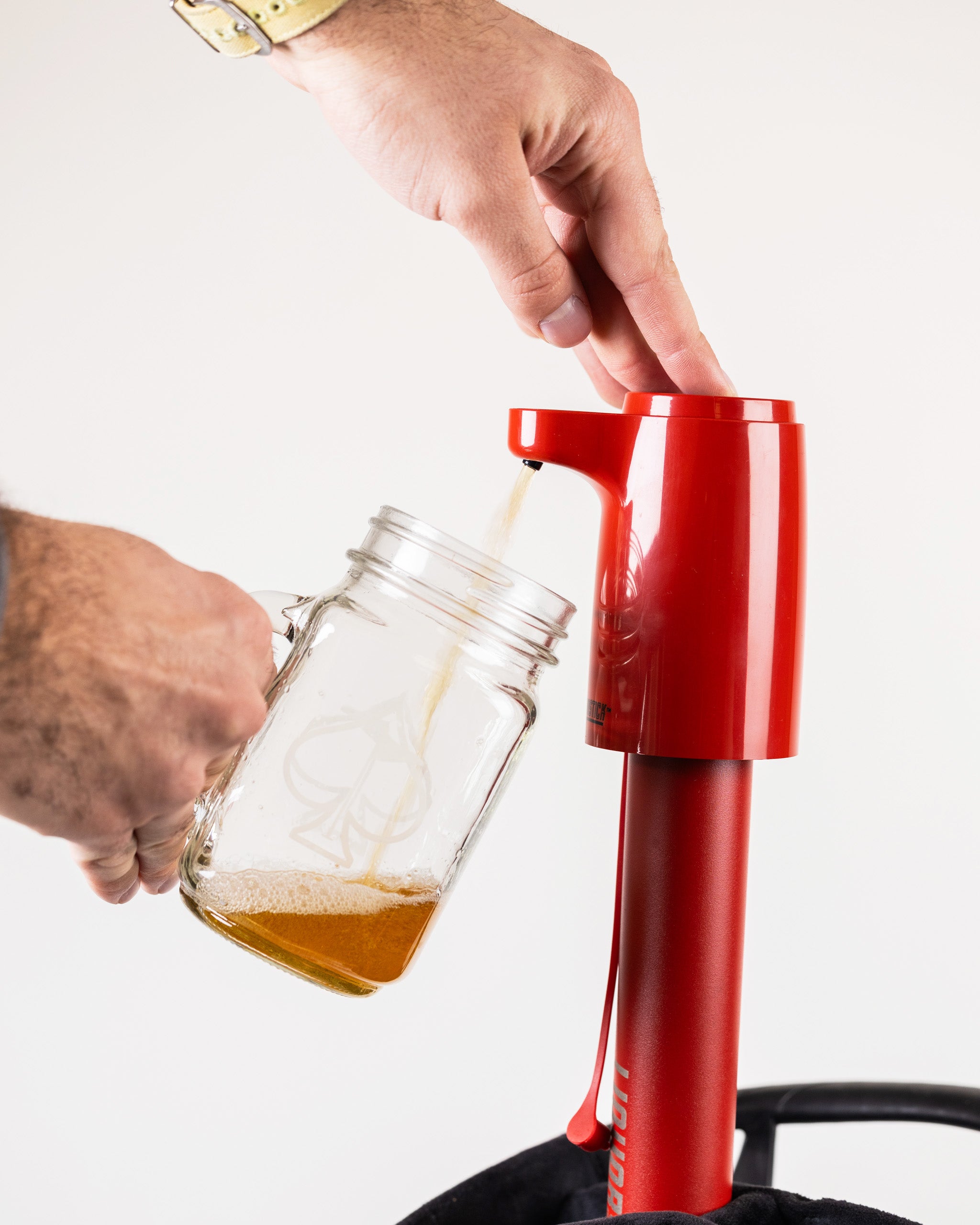 Red beer dispenser with a tall, sleek design, dispensing into a mason jar, perfect for bold golf-themed accessories.