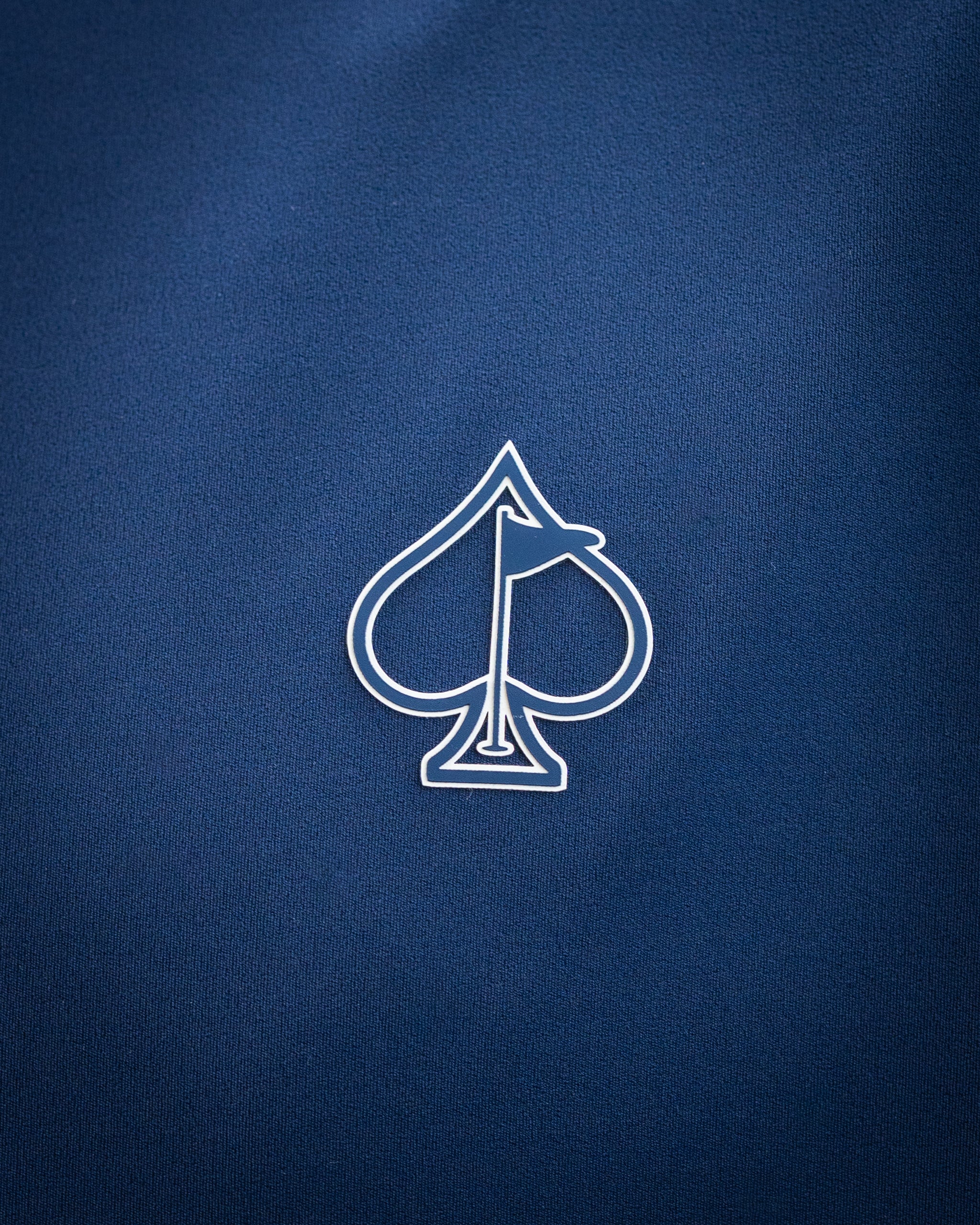 Close-up of a navy blue golf accessory with a white spade and flag logo, highlighting bold, unique design for standout gol...