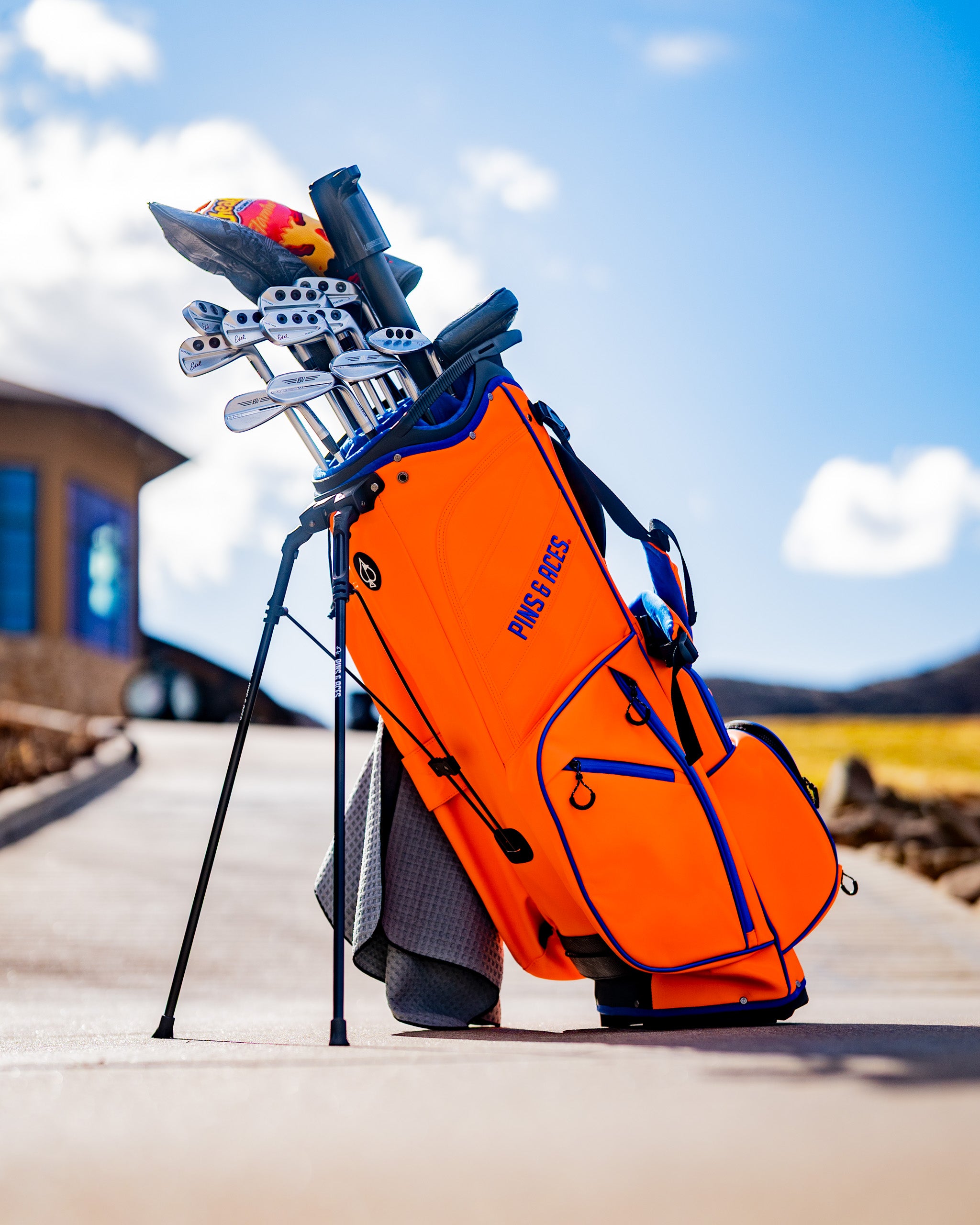 Player Preferred™ Golf Bag in vibrant orange, featuring multiple pockets and a sleek design, positioned against a neutral background.