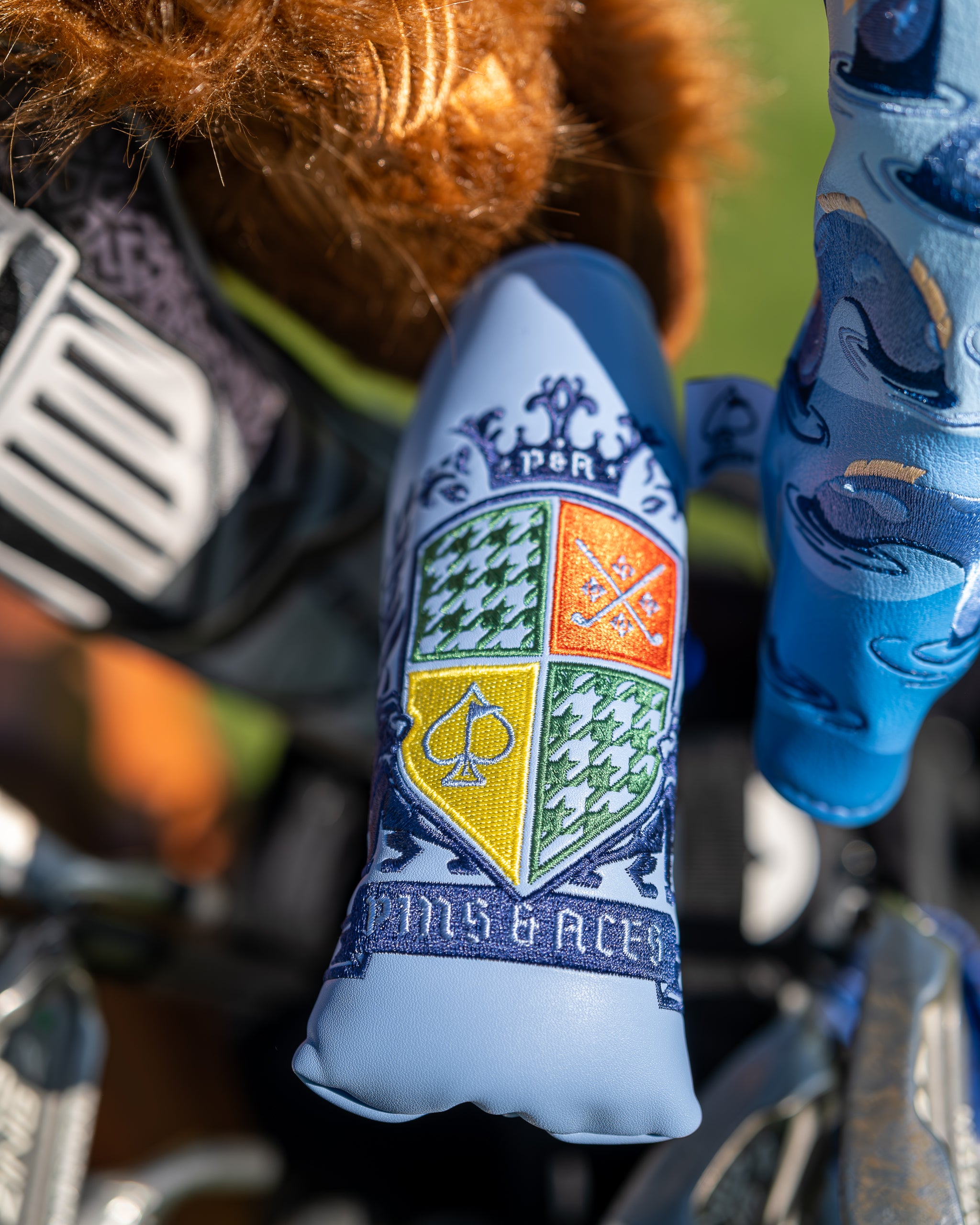 "Coat of Arms Blade Putter Cover featuring a royal emblem design, displayed in a lifestyle setting."