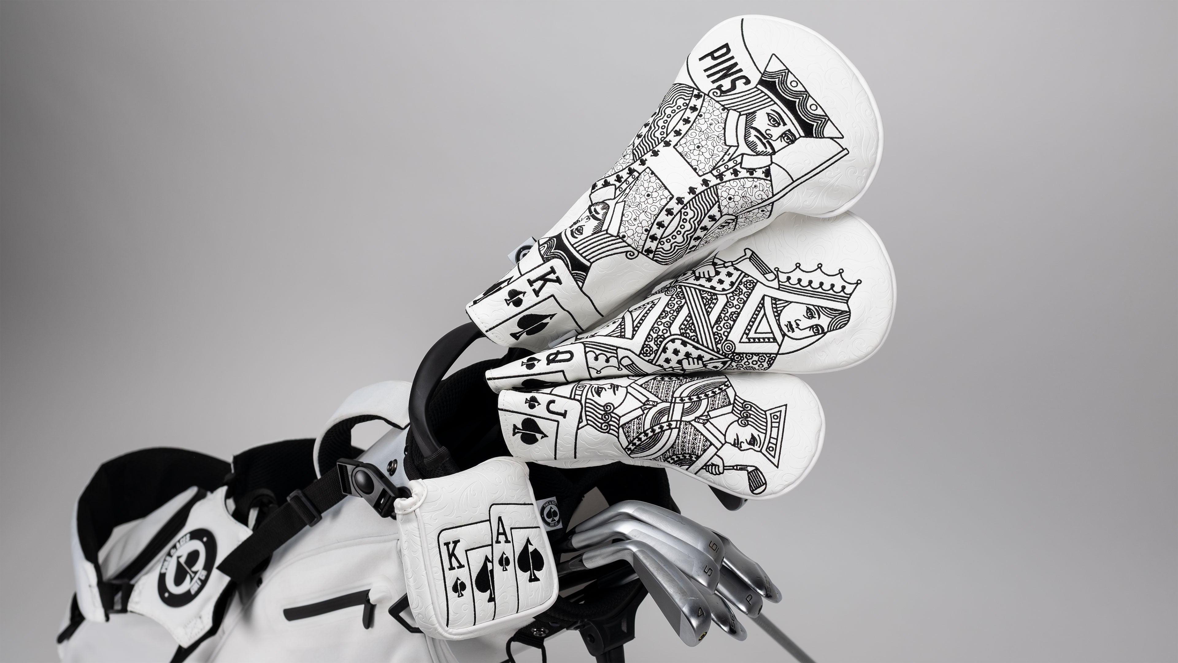 Golf headcovers featuring bold black and white playing card designs, including king, queen, and ace motifs.