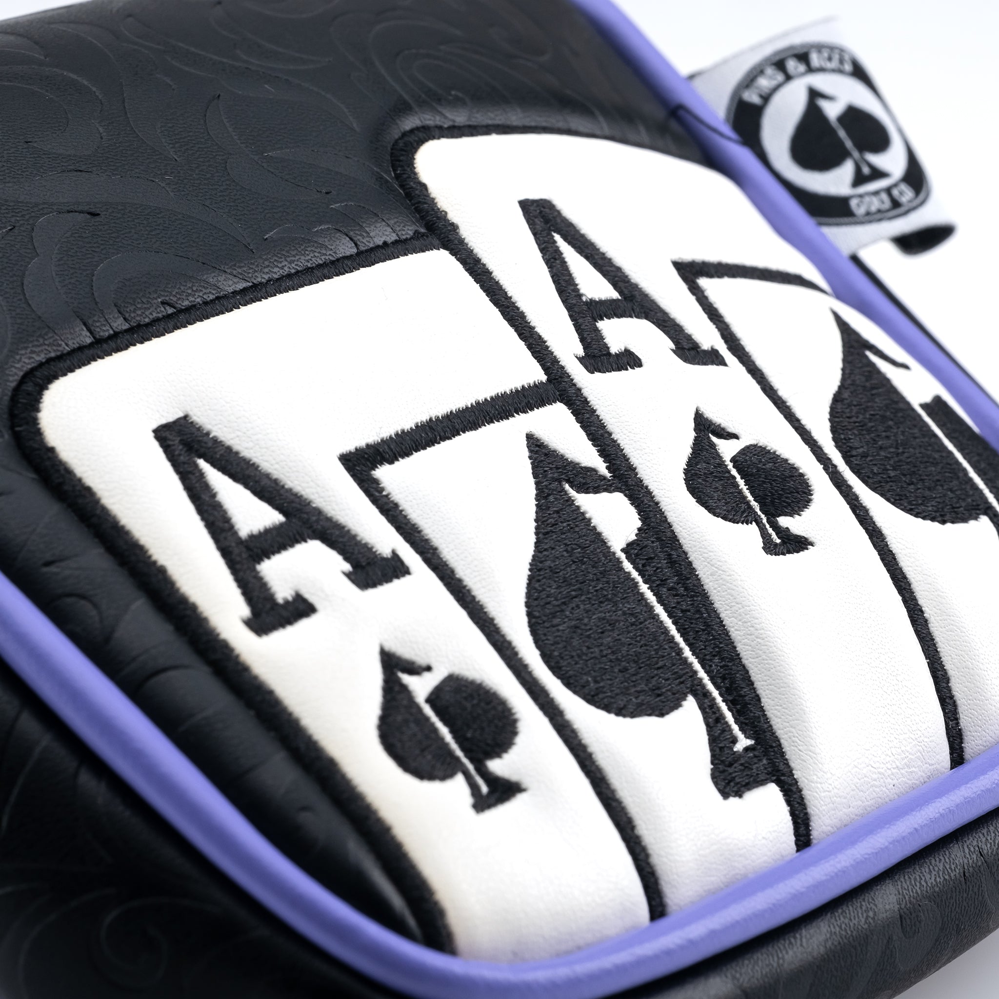 Close-up of bold black and white golf headcover with spade and club symbols, accented by purple trim for a standout look.