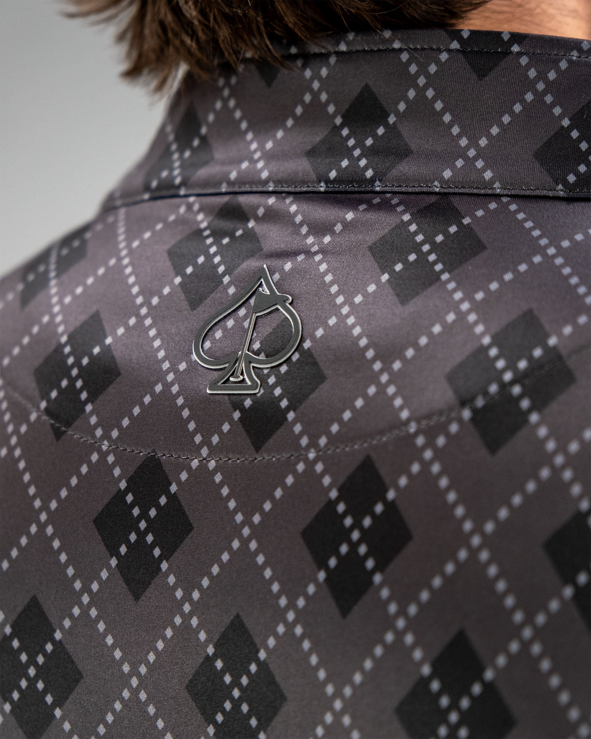 Close-up of the back of a London Fog Pullover featuring a diamond pattern and a small logo in the center.