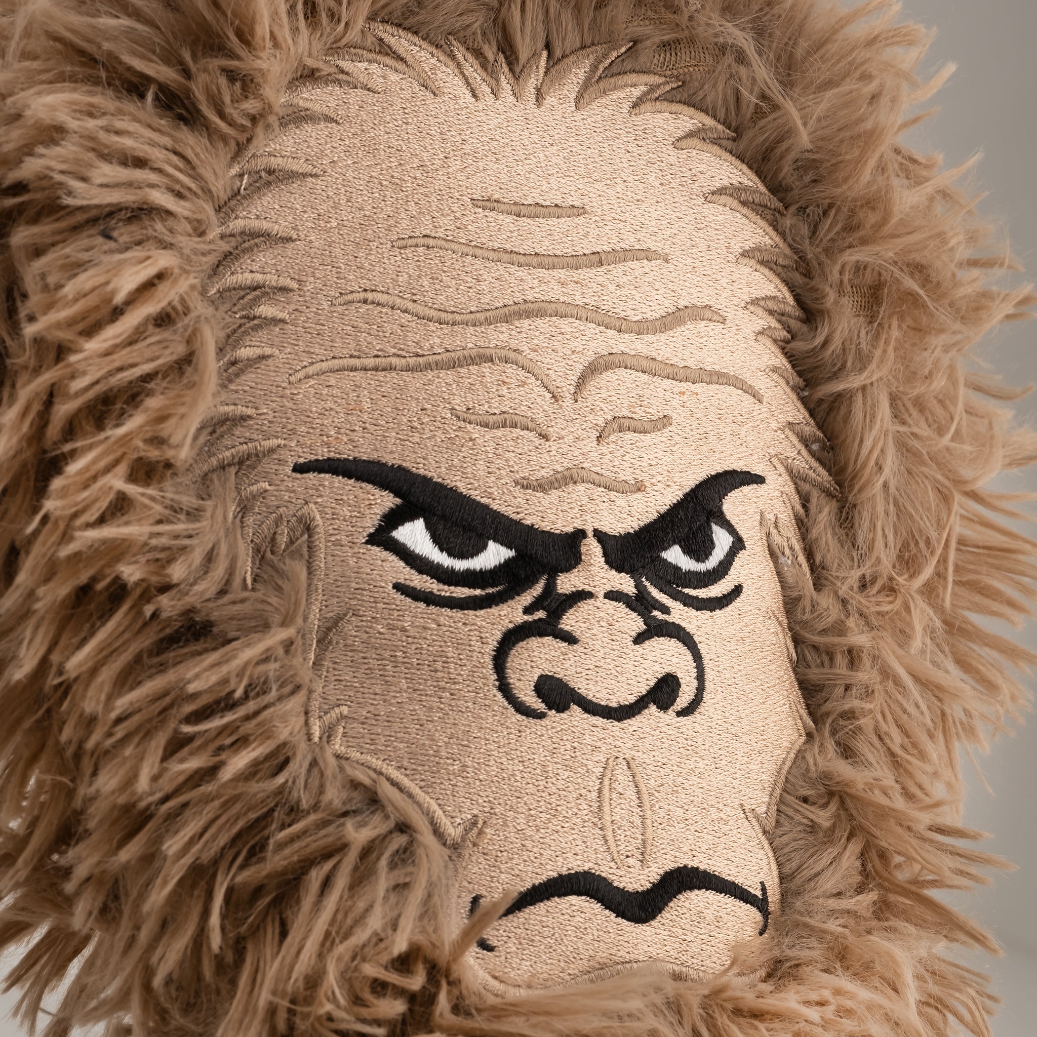 Close-up of a furry beige golf club headcover with an embroidered angry gorilla face, perfect for bold golf style.