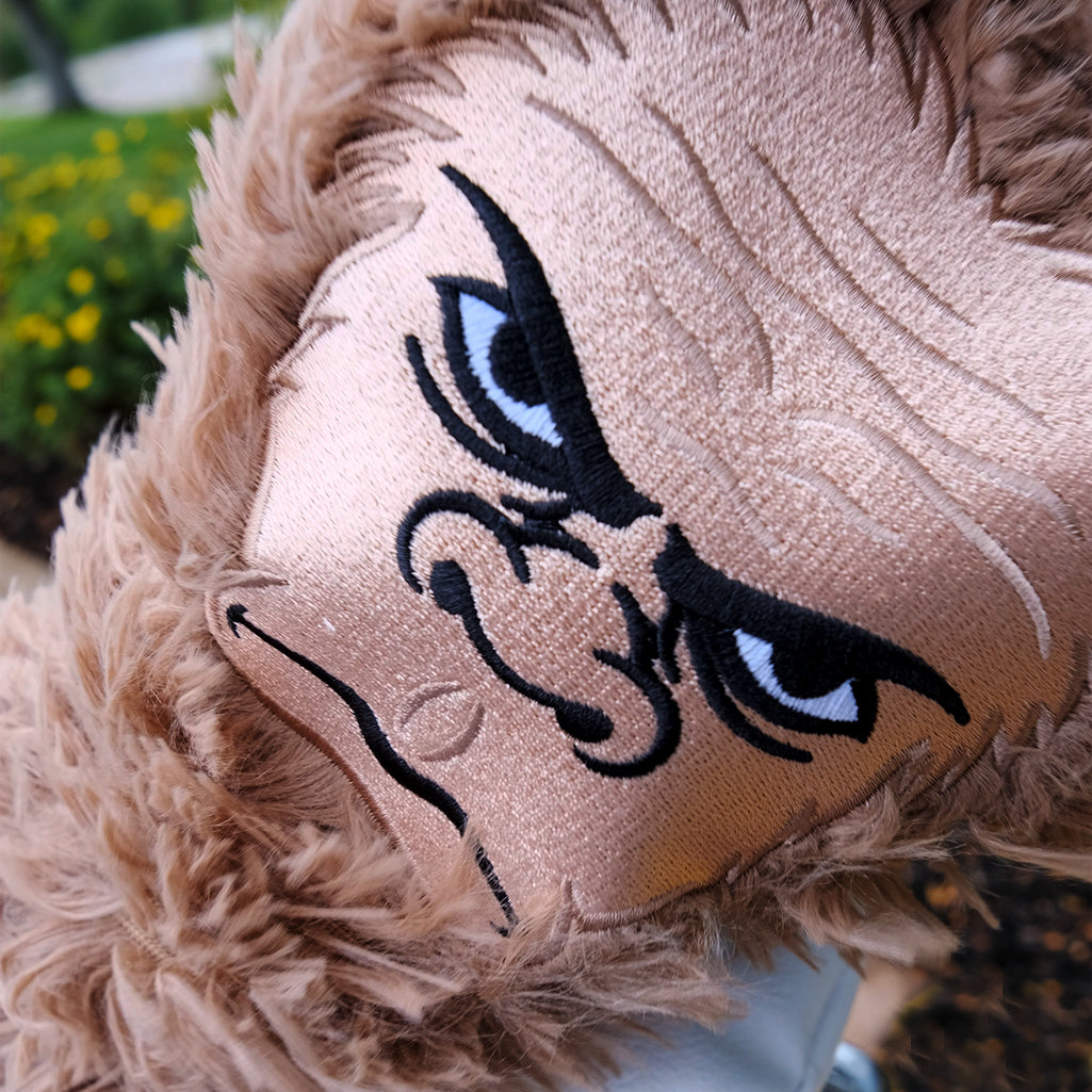 Close-up of a plush beige golf headcover with bold embroidered cat face, featuring striking black and white eyes, perfect ...