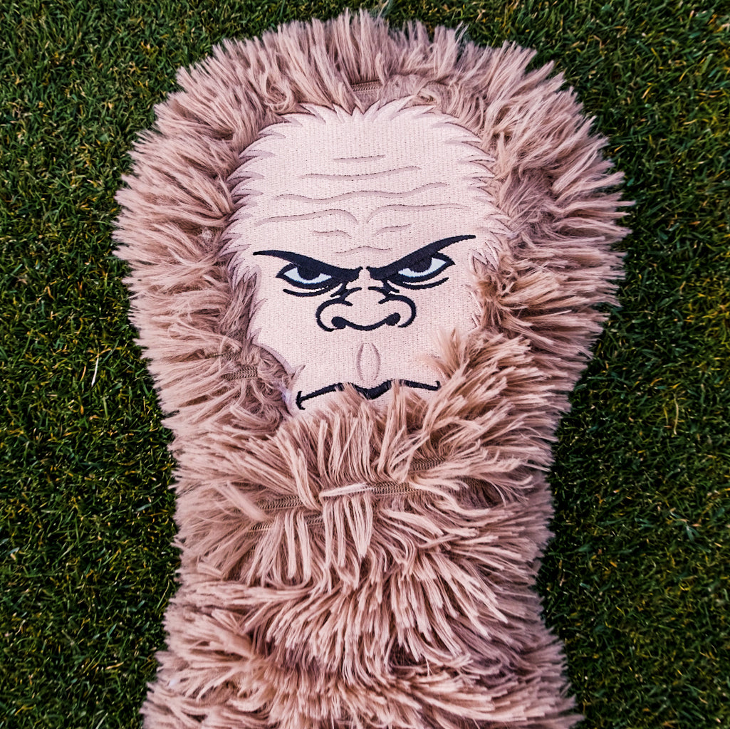 Furry pink golf club headcover with fierce, embroidered gorilla face featuring intense eyes and a stern expression.