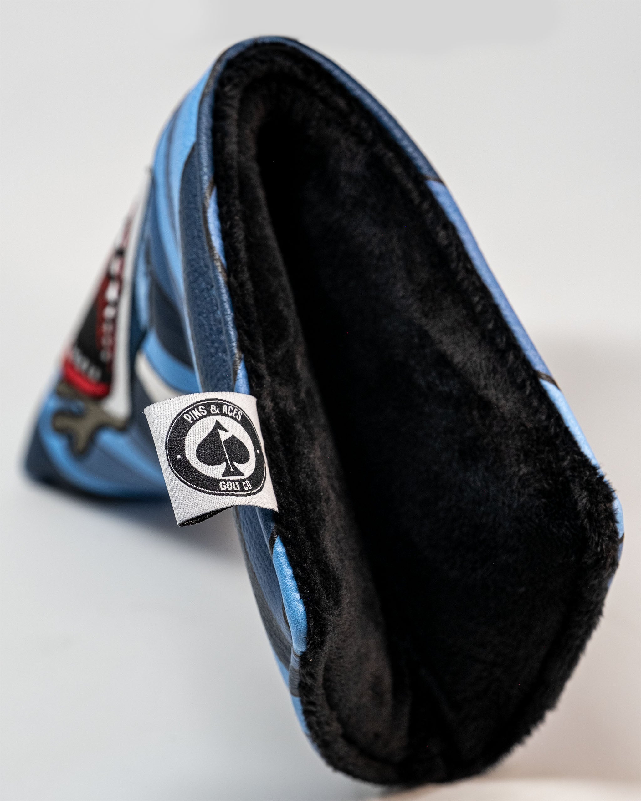 Colorful golf headcover with black fleece lining, featuring bold graphics and a "Pinks & Aces Golf Co" tag.