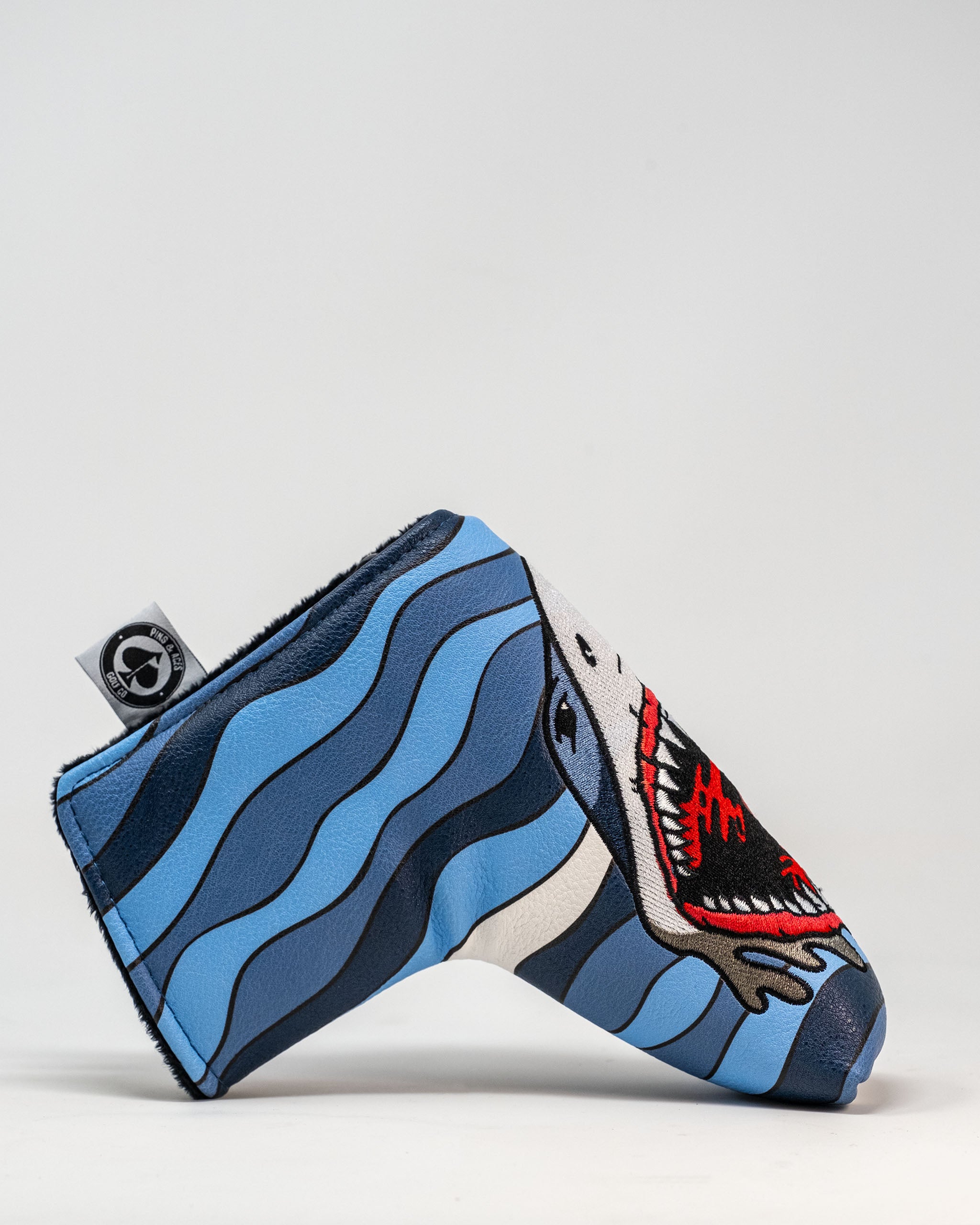 Shark Attack Blade Putter Cover featuring a playful shark design on a vibrant blue background.